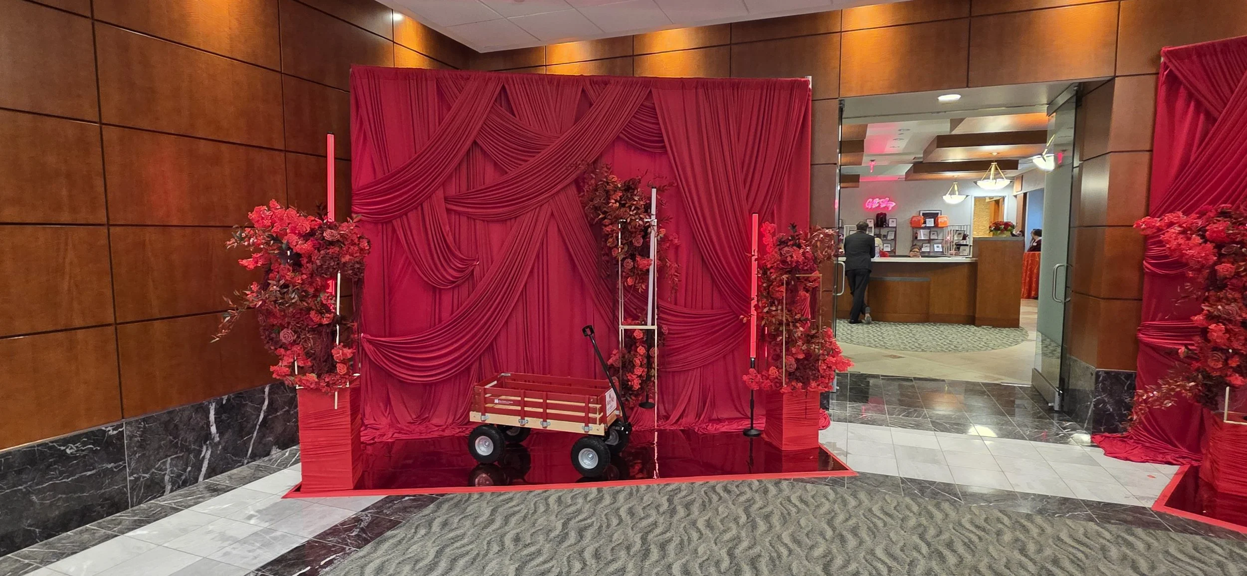The Riley Children’s Hospital RED Gala photo backdrop designed by JPS Events at Regions Tower, featuring dramatic red drapery, custom in-house floral arrangements, and luxury downtown Indianapolis venue styling.