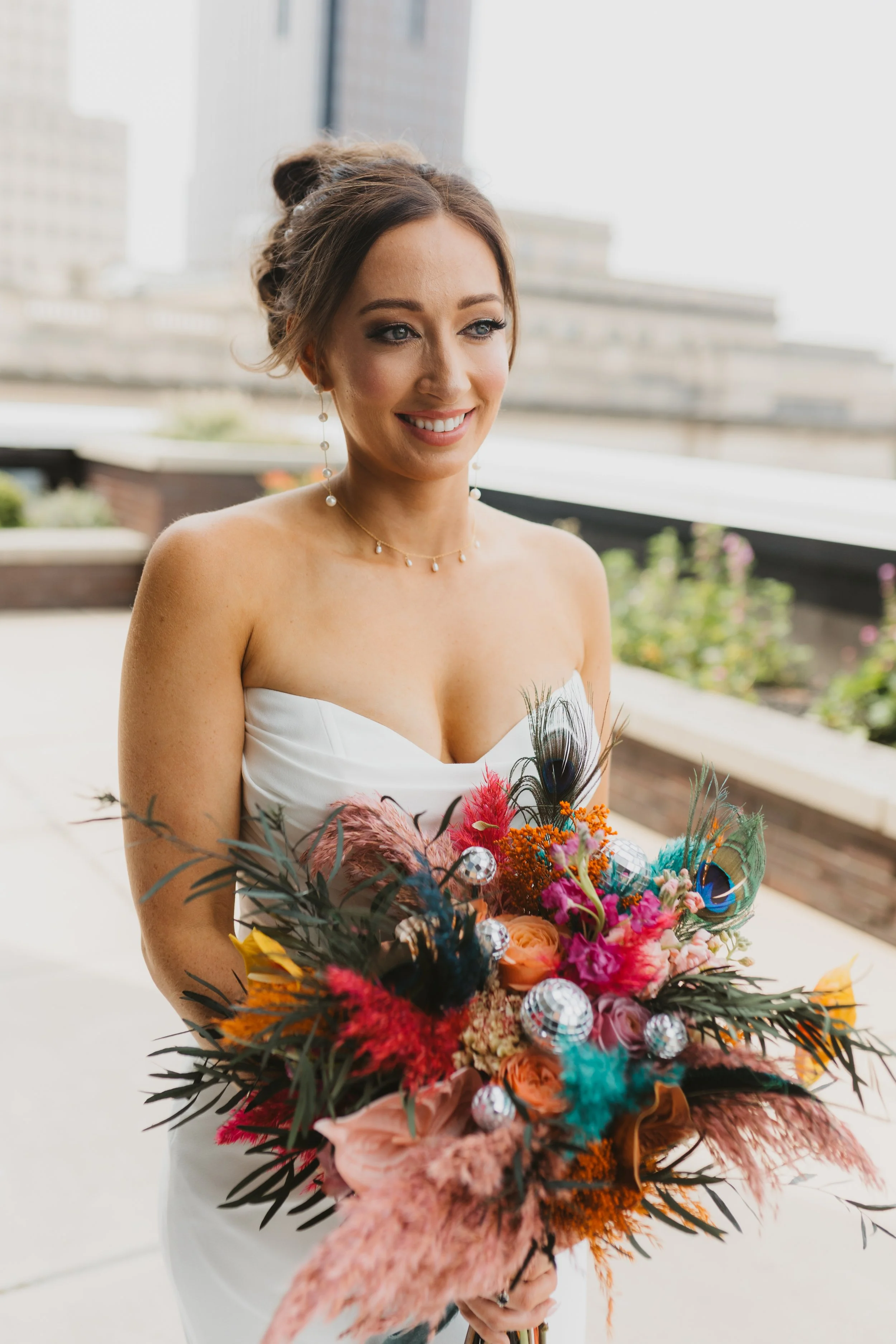 Bride holding a colorful bouquet created by the in-house floral team at JPS Events at Regions Tower. Features over-the-top bridal floral styling at wholesale pricing & 360 rooftop skyline view photo ops in downtown Indy.