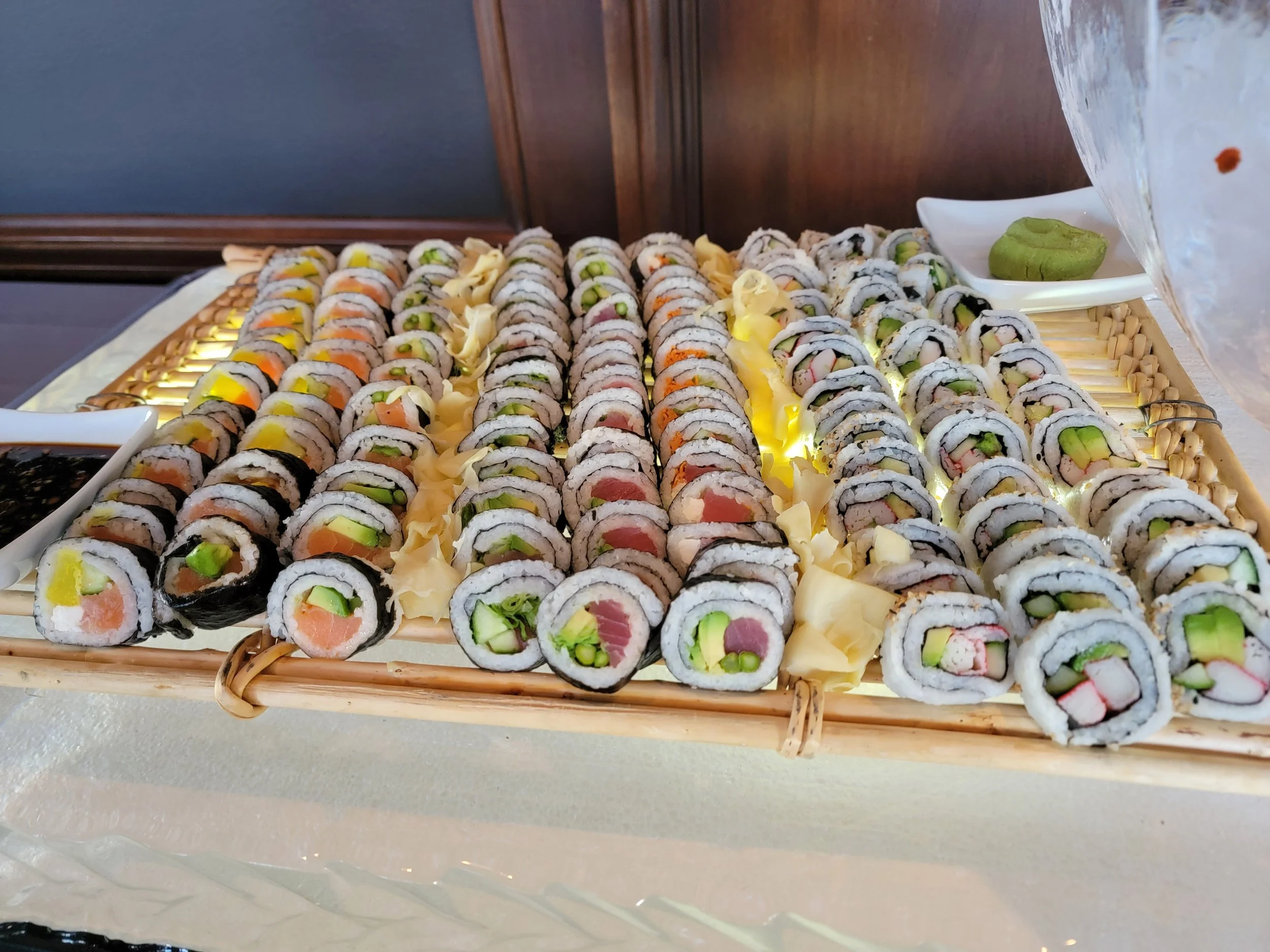 Assorted sushi rolls arranged neatly on a woven bamboo tray, with small dishes of soy sauce and wasabi on the side—imaginative takes on classic wedding food from luxury in-house catering at JPS Events at Regions Tower in Downtown Indy.