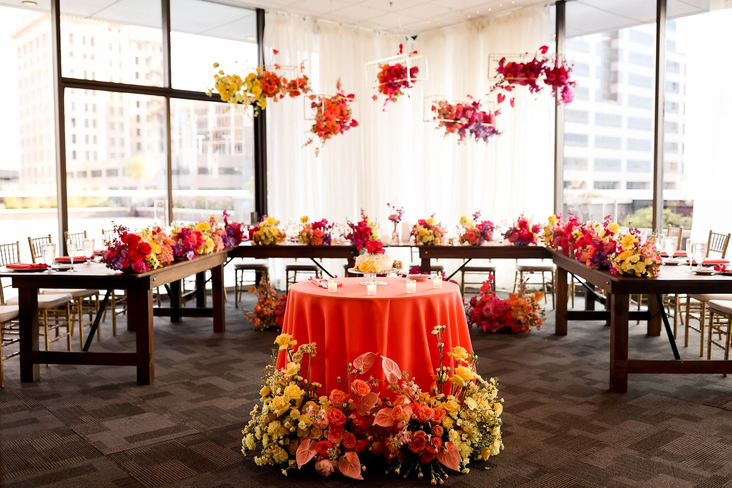 Vibrant head table design featuring floating colorblocked floral arrangements by the in-house floral team at JPS Events at Regions Tower, offering custom all-inclusive decor and floor-to-ceiling city views in downtown Indy.