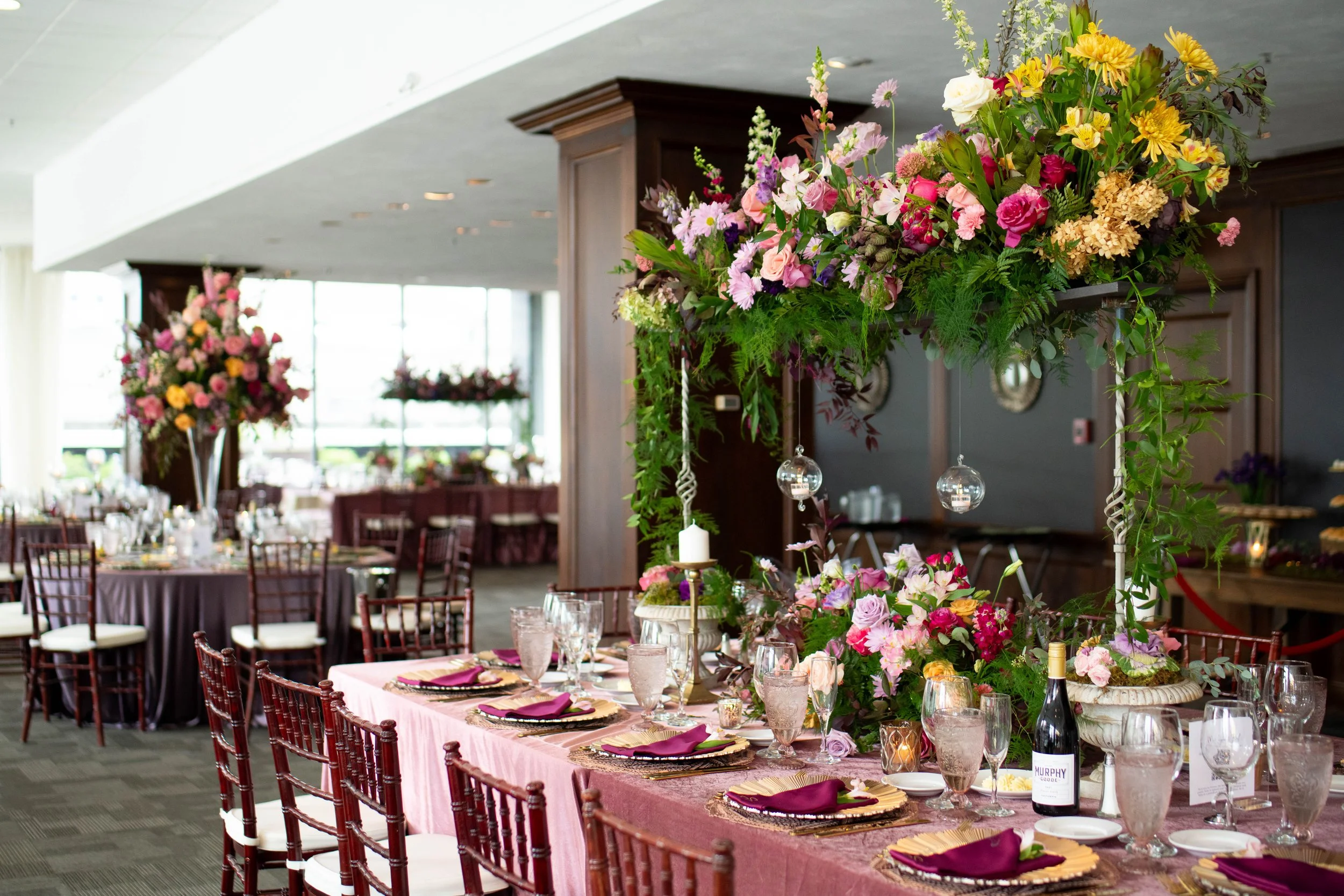 Lush, over-the-top tall centerpiece designed by the in-house floral team at JPS Events at Regions Tower. Highlights custom color palettes at wholesale pricing, polished white marble floors, and chef-driven catering in Indy.