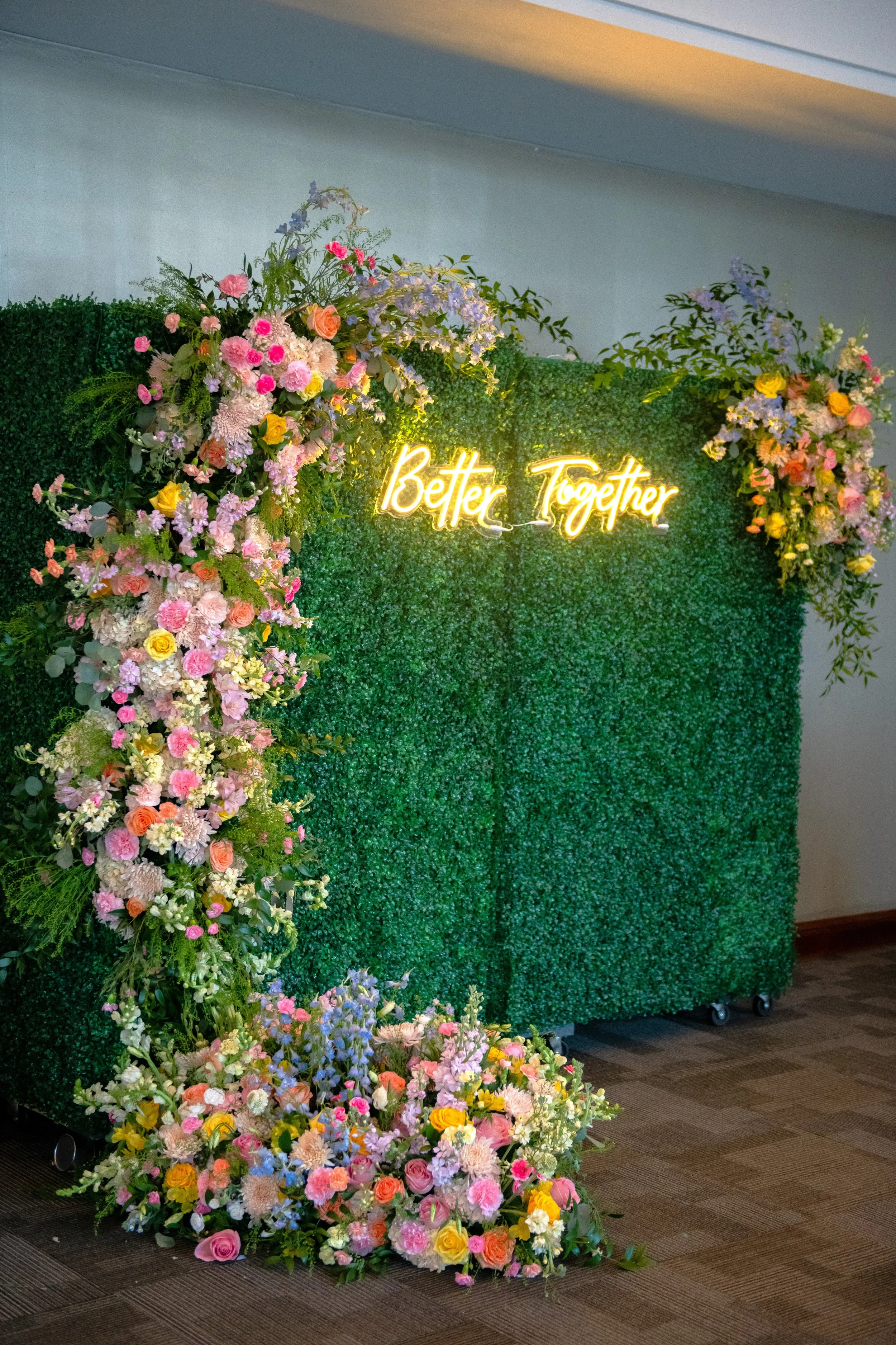 Custom 'Better Together' neon sign on a foliage photo backdrop designed by JPS Events at Regions Tower. Showcases our in-house floral team's ability to create bespoke, trendy photo moments for luxury weddings in downtown Indy.