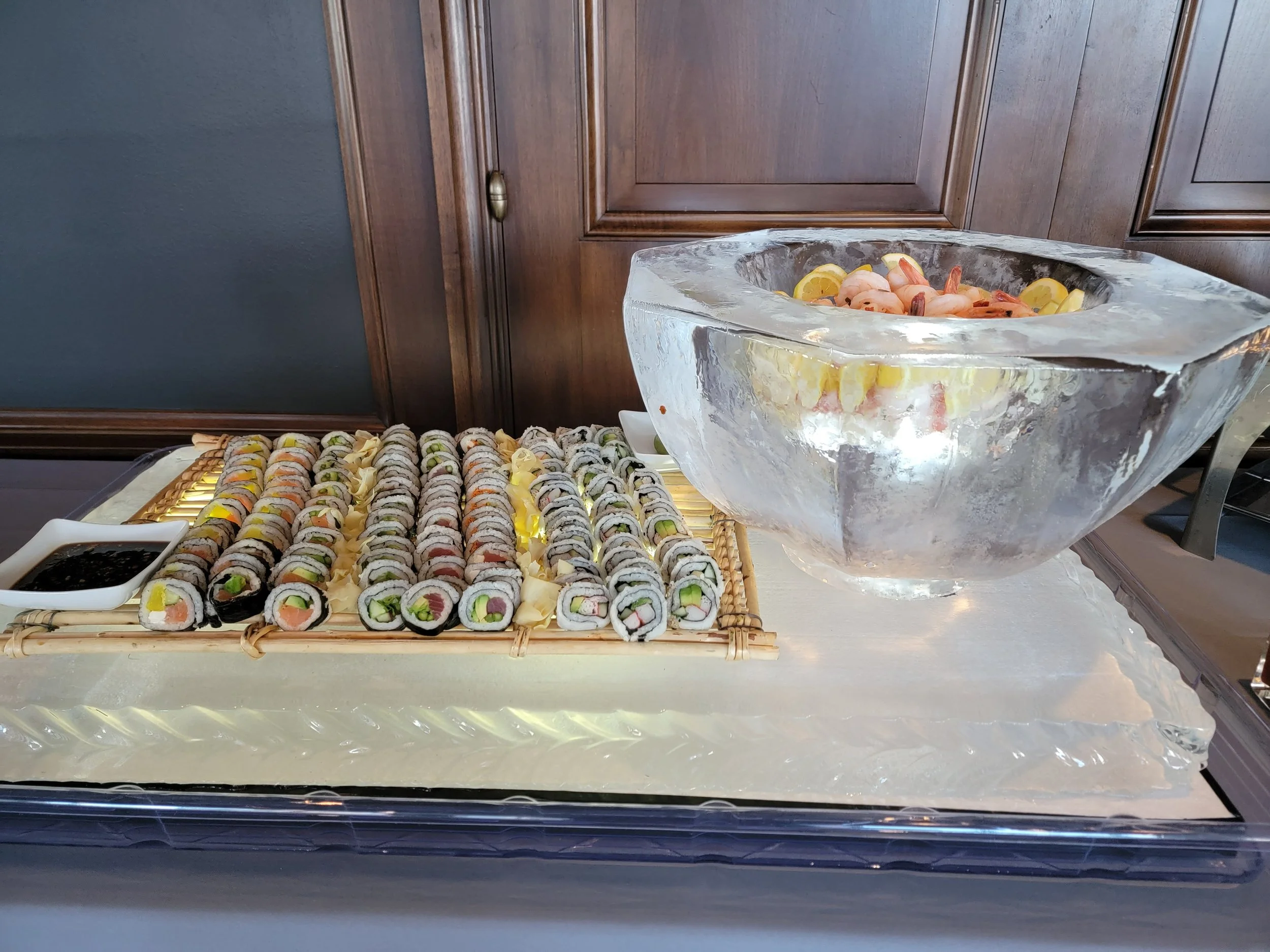 Display of assorted sushi rolls and a large ice bowl with shrimp and lemons prepared by the chef-driven in-house catering team at JPS Events at Regions Tower, an all-inclusive luxury wedding venue in Downtown Indianapolis.