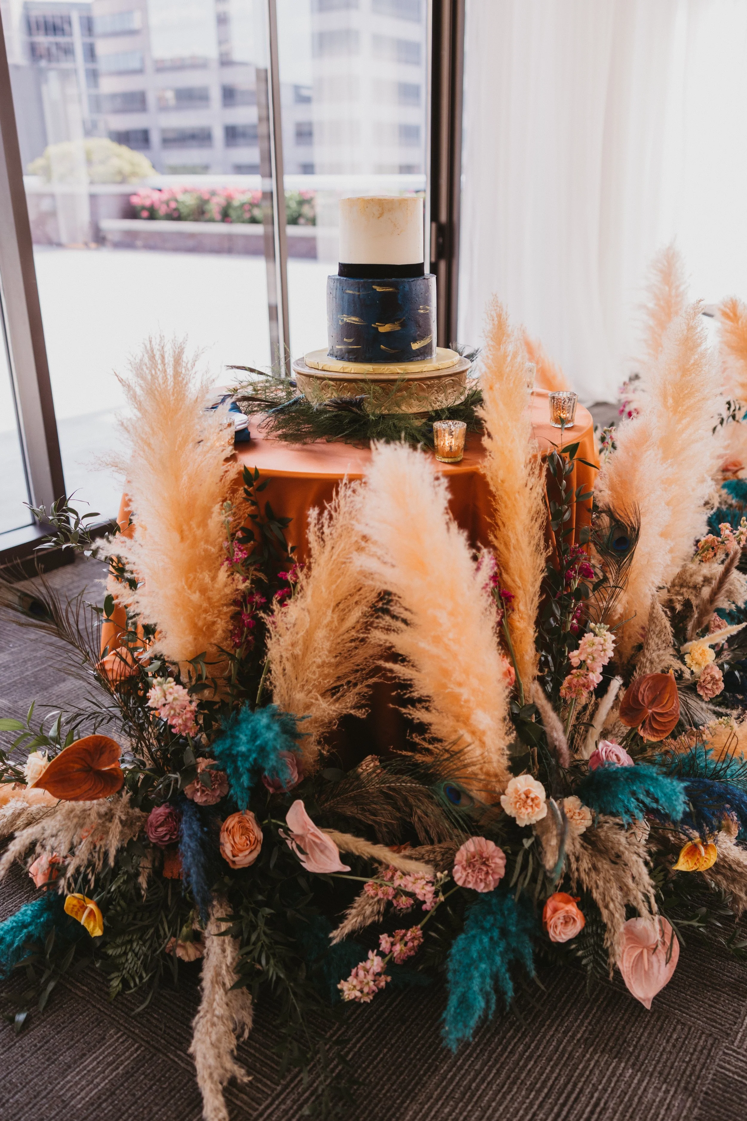 Custom pampas grass and floral cake table design at JPS Events at Regions Tower. Designed by our in-house team to showcase our collaborative design process, custom tablescaping, and light-filled indoor ballroom in downtown Indy.