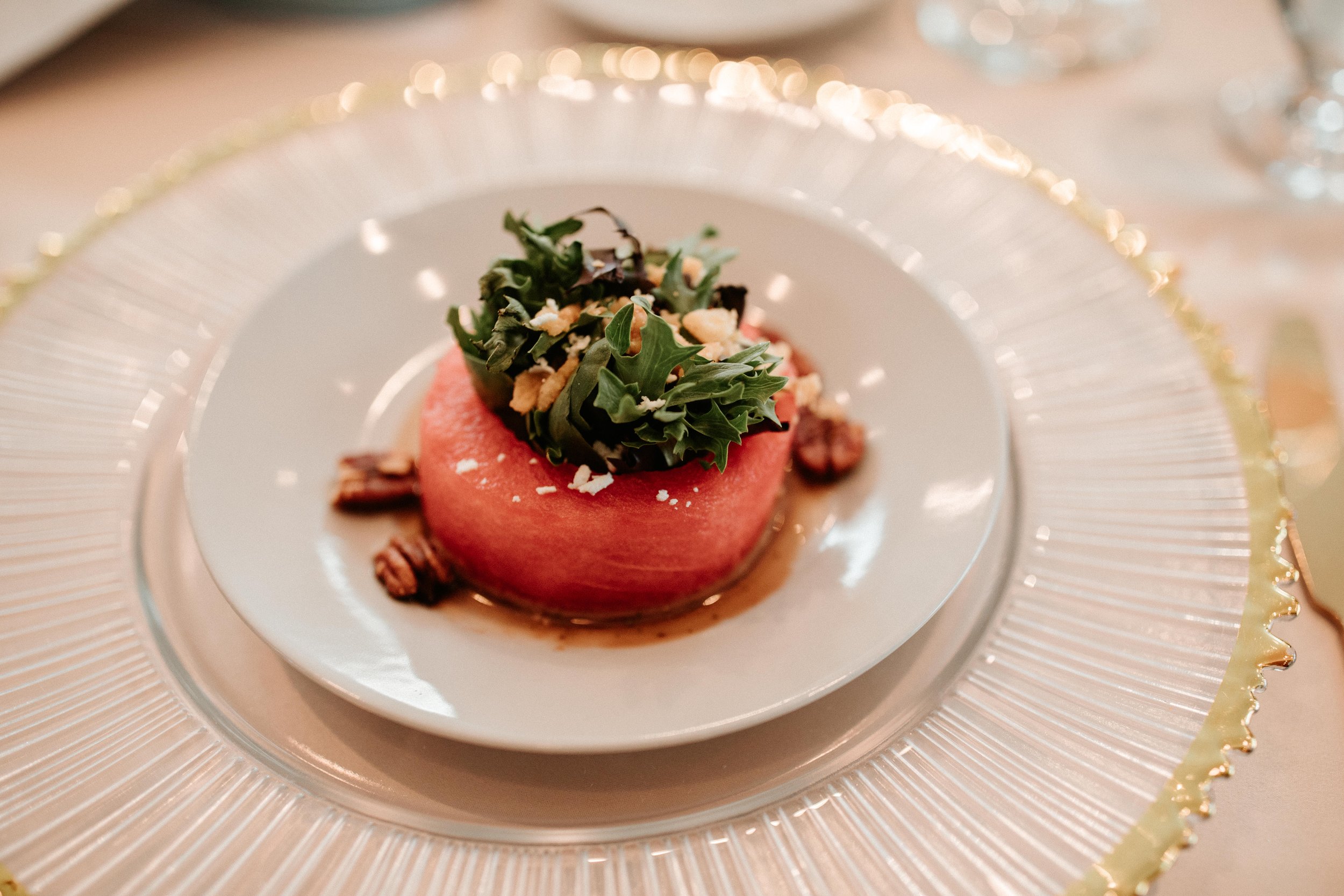 Chef curated bespoke menus from luxury in-house catering at JPS Events at Regions Tower in Downtown Indy: a dessert featuring pink mousse with green leaves, nuts, and chocolate on a white dish and glass charger plate.