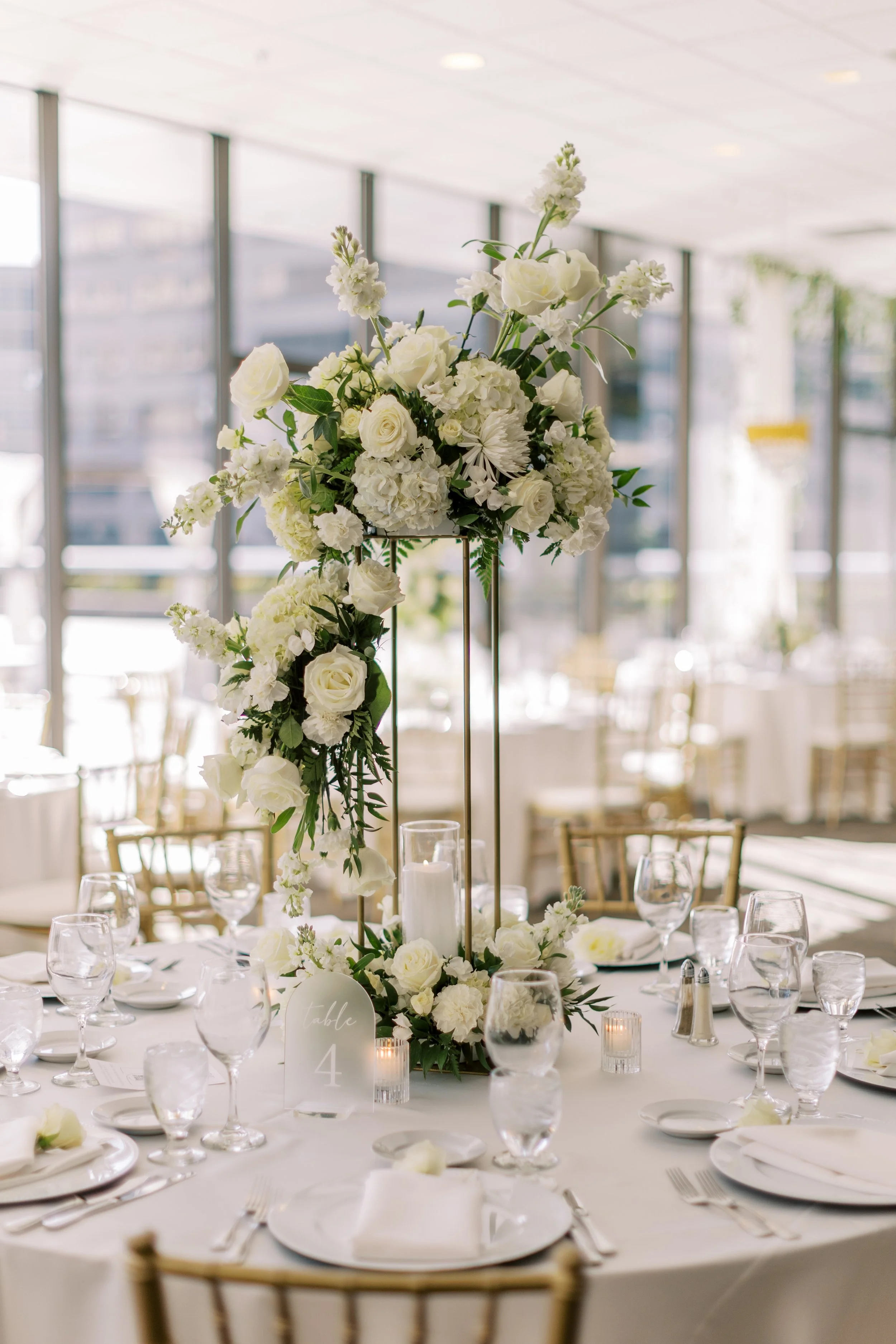 Tall luxury white floral centerpiece created by the in-house florists at JPS Events at Regions Tower. Features over-the-top floral design at wholesale pricing, polished white marble flooring, and zero late-out fees in Indy.