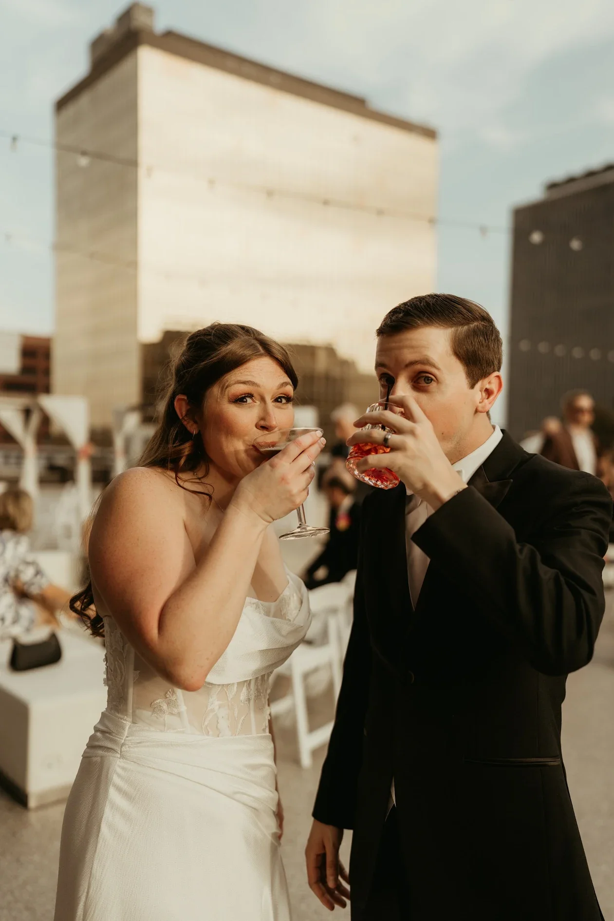 A bride and groom happy at their wedding reception on the JPS Events private rooftop in front of Indy's iconic gold building, enjoying signature drinks from the in-house bar program.