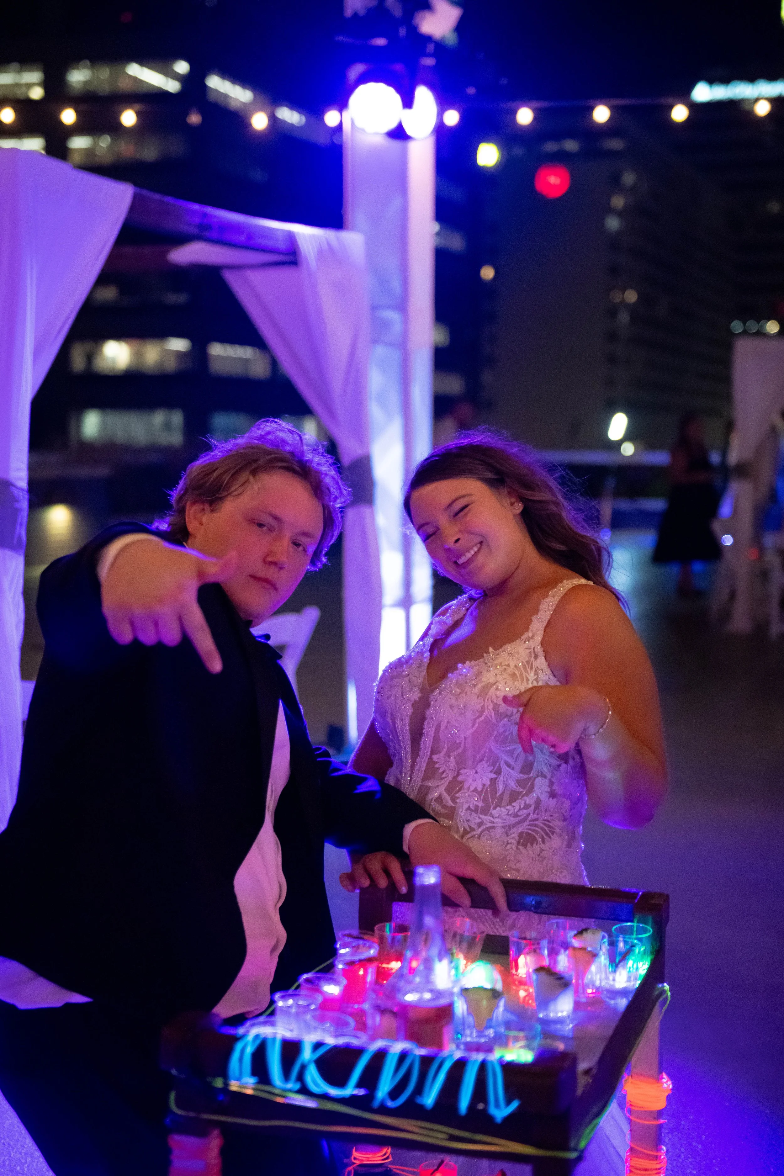 Couple with a light up shot cart at a late-night reception at JPS Events at Regions Tower. Features custom interactive lounge activations, night skyline views, string lighting, & zero late-out fees in Indy