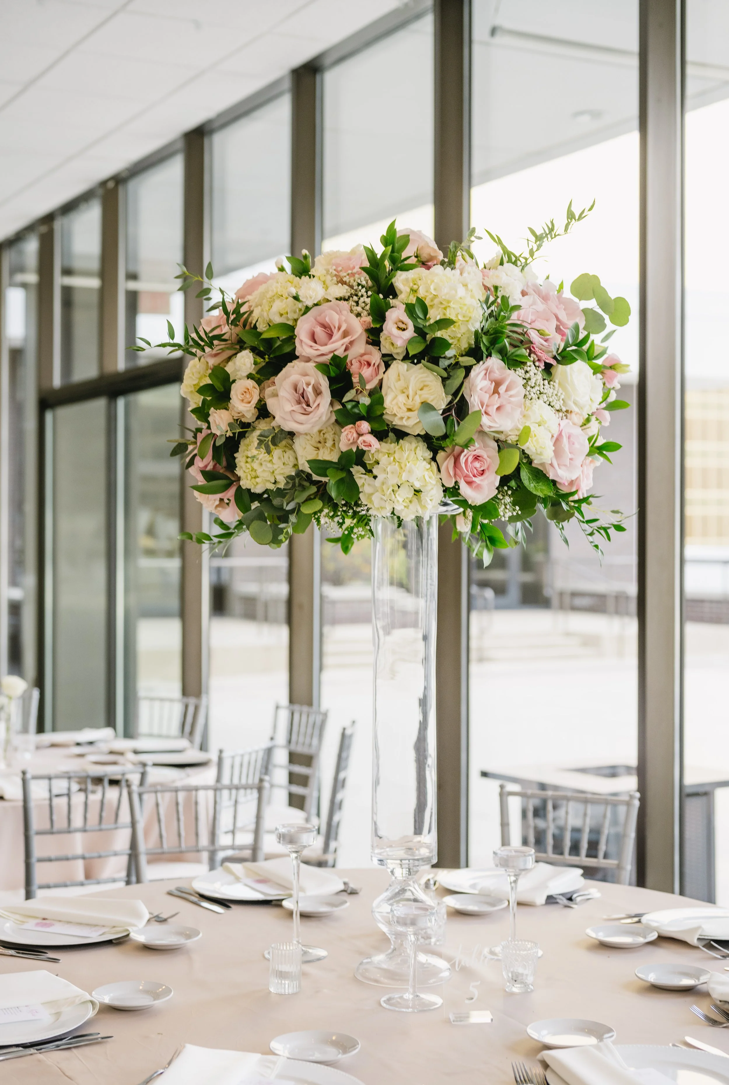 Classic white rose elevated centerpiece on polished white marble floors at JPS Events at Regions Tower. Features over-the-top in-house floral design at wholesale pricing with hands-on owner day-of coordination in downtown Indy.