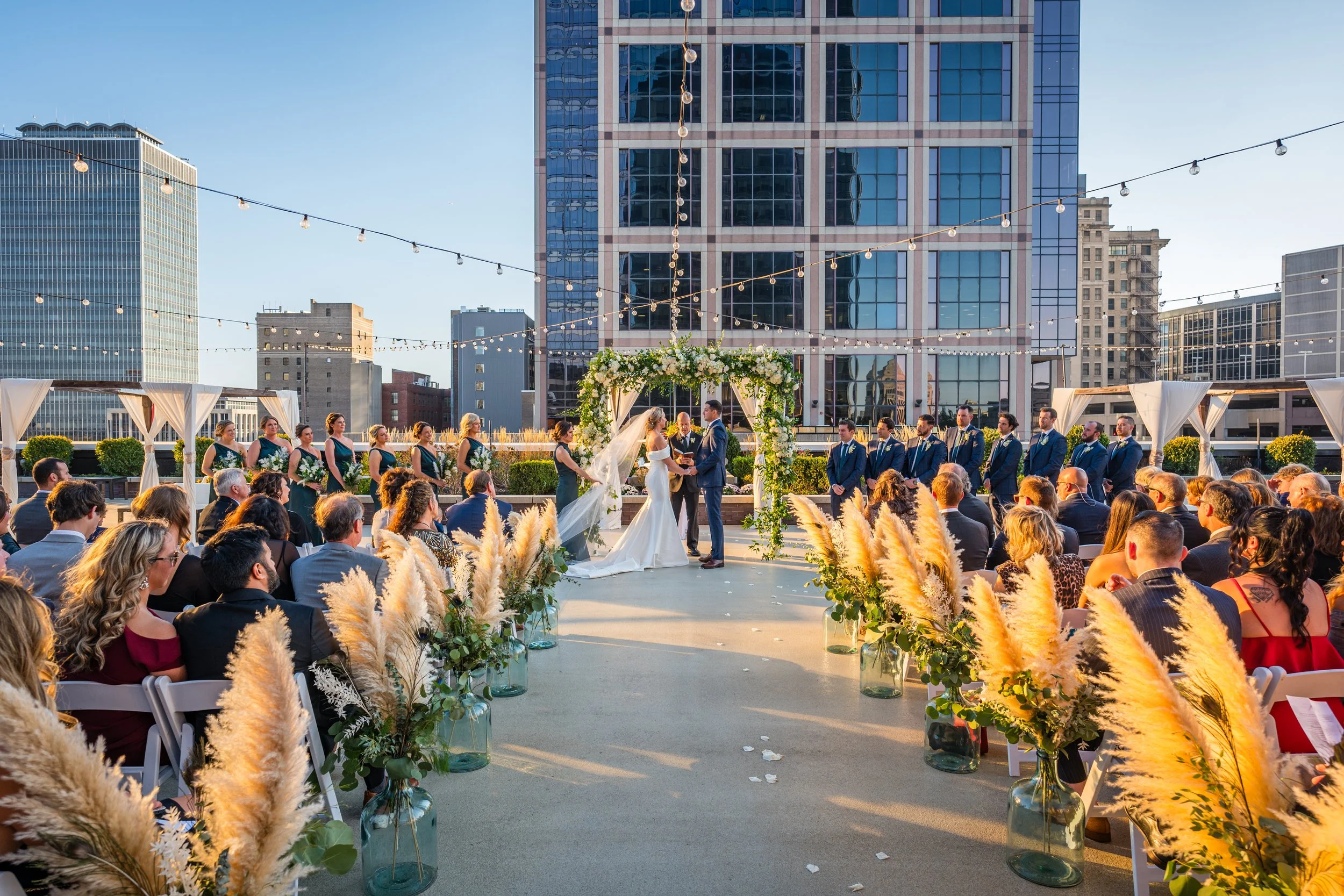 Outdoor rooftop wedding ceremony on the 5th-floor terrace at JPS Events at Regions Tower. Features custom over-the-top floral arches at wholesale pricing, 360 skyline views, and zero late-out fees in downtown Indy