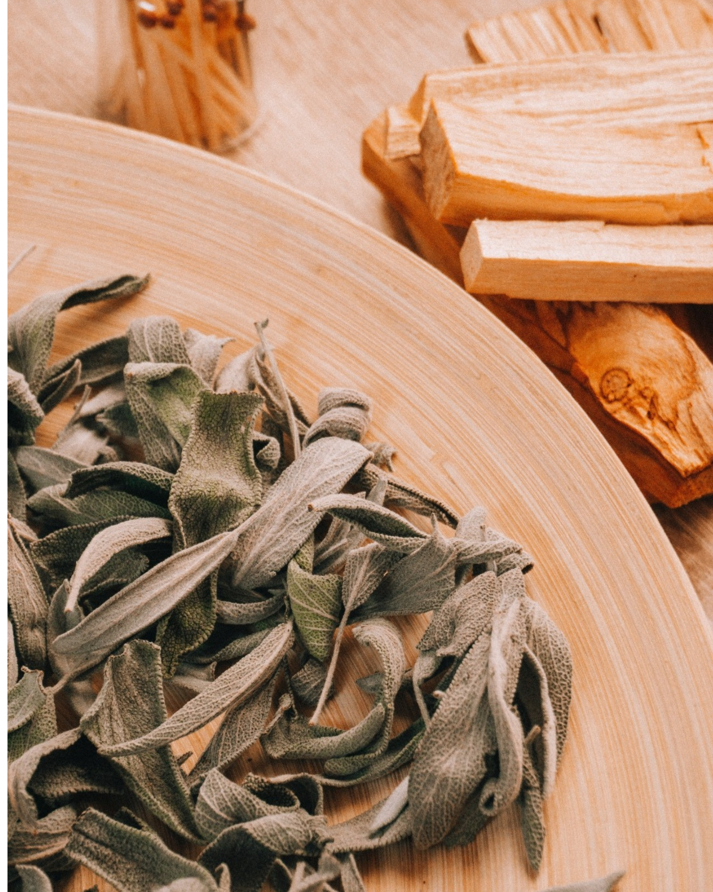 Dried sage leaves, a bamboo plate, and pieces of wood on a wooden surface.
