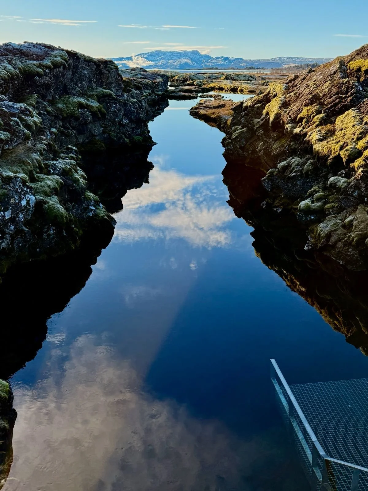 Water, rocks and ladder down into it with mountains in the background. Silfra fissure: between North American and Eurasian continental plates,