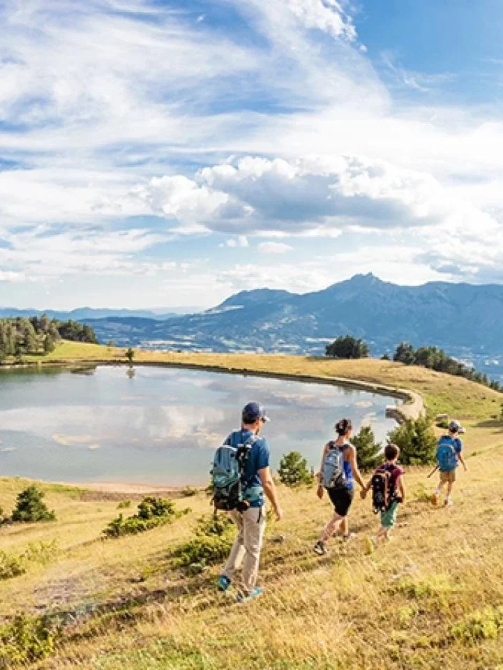 Water reservoir on canal de Malcros with family of hikers against mountain backdrop