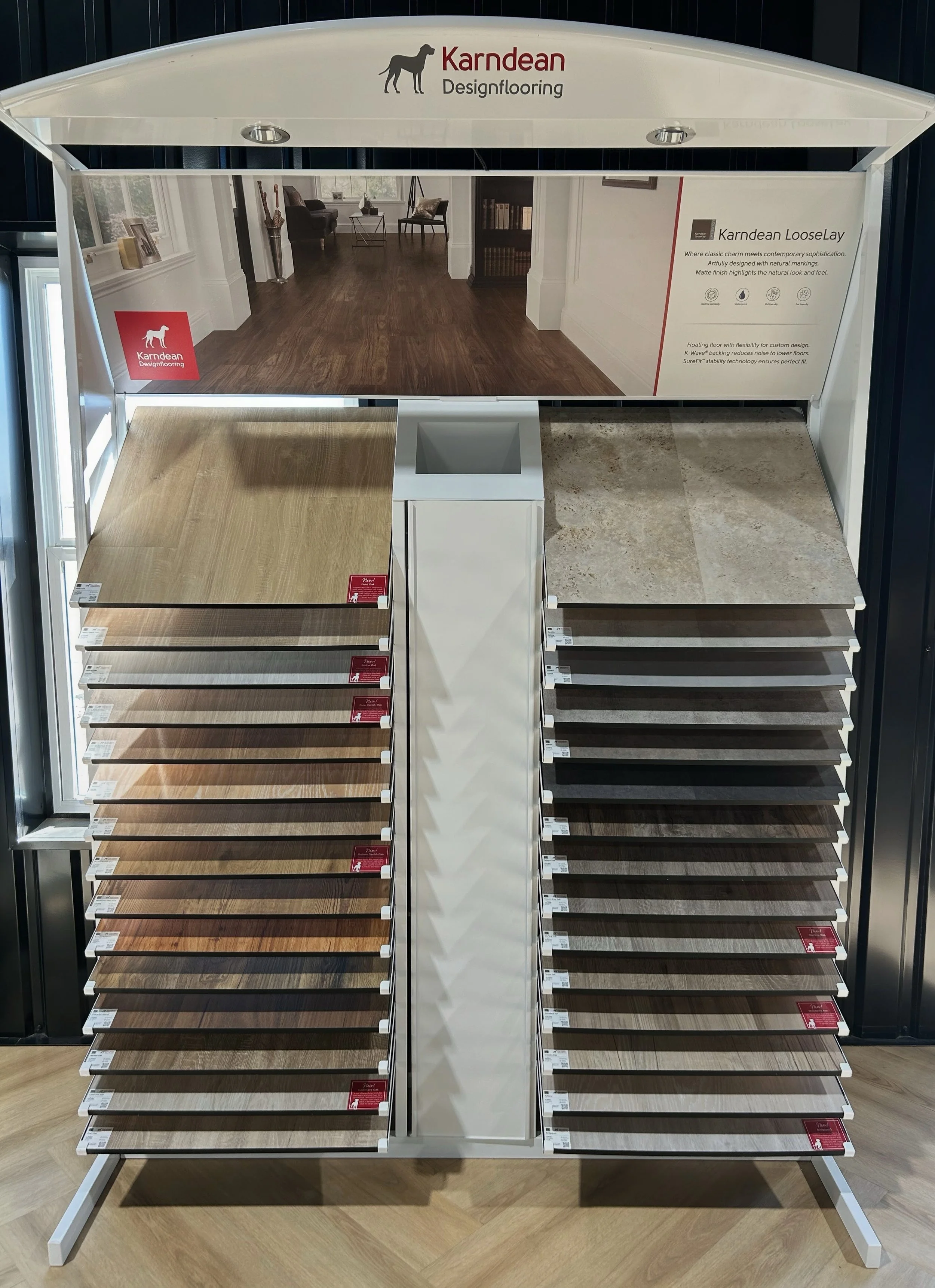 Display of wood flooring samples in various shades, arranged on a stand in a flooring store.