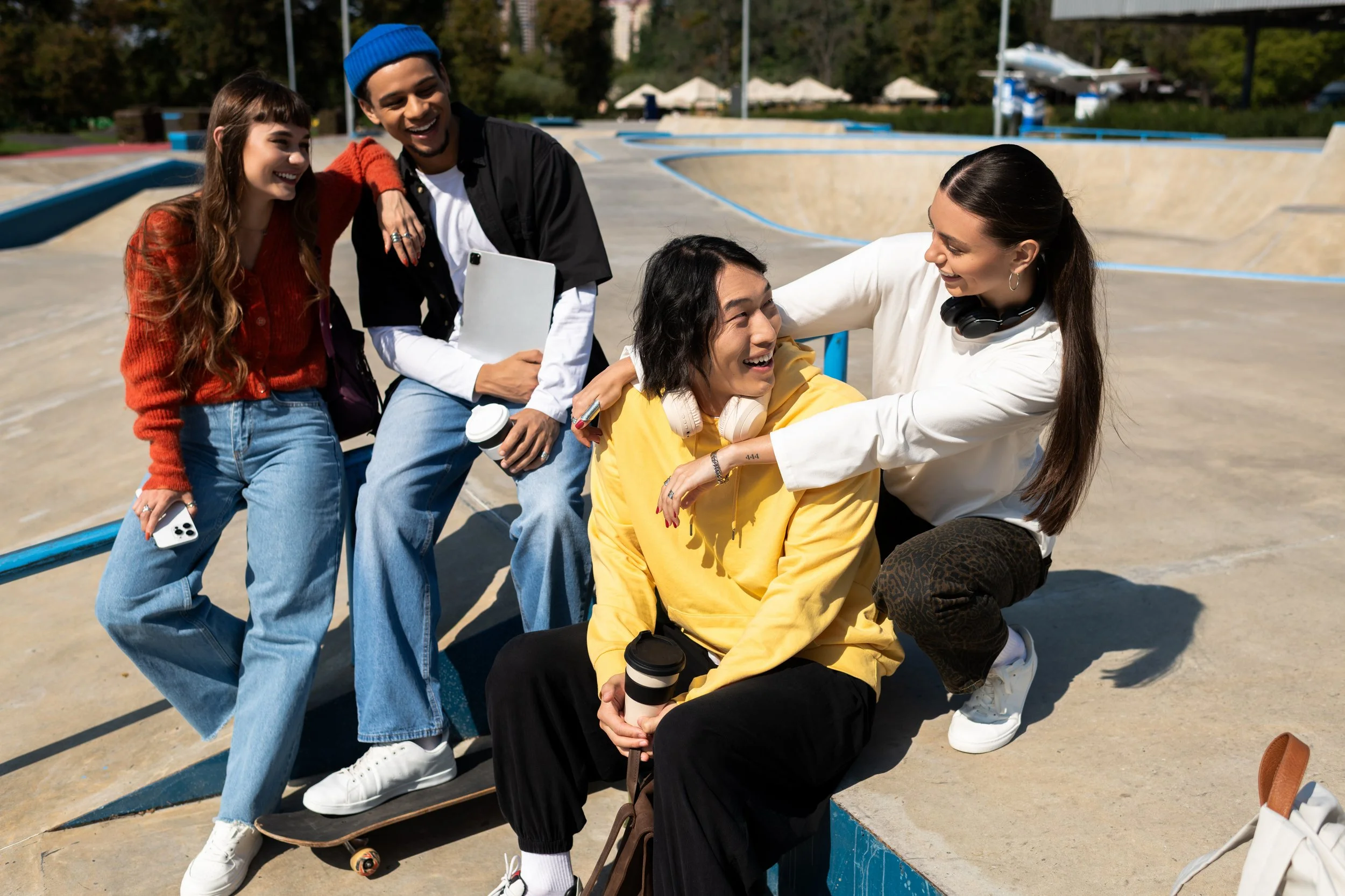 Group of five friends at an outdoor skate park, enjoying each other's company and smiling.