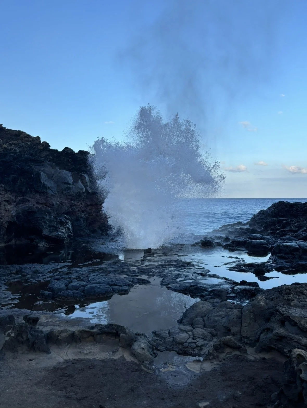 Ocean waves crashing against rocky cliffs during daylight.