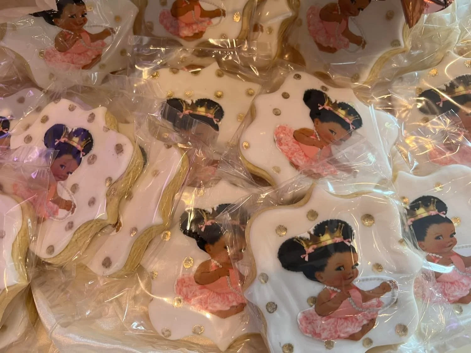 Decorated sugar cookies with a princess theme, featuring a girl with black hair in a pink dress and gold accents, individually wrapped in clear plastic.