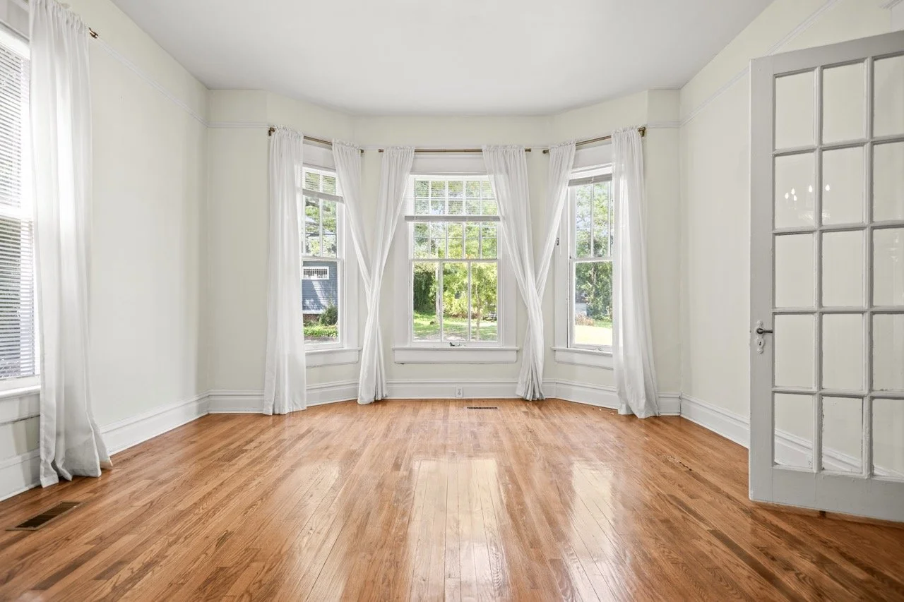 Bright living room with large windows and hardwood floors captured using professional real estate photography in Fayetteville NC to increase buyer interest and online engagement
