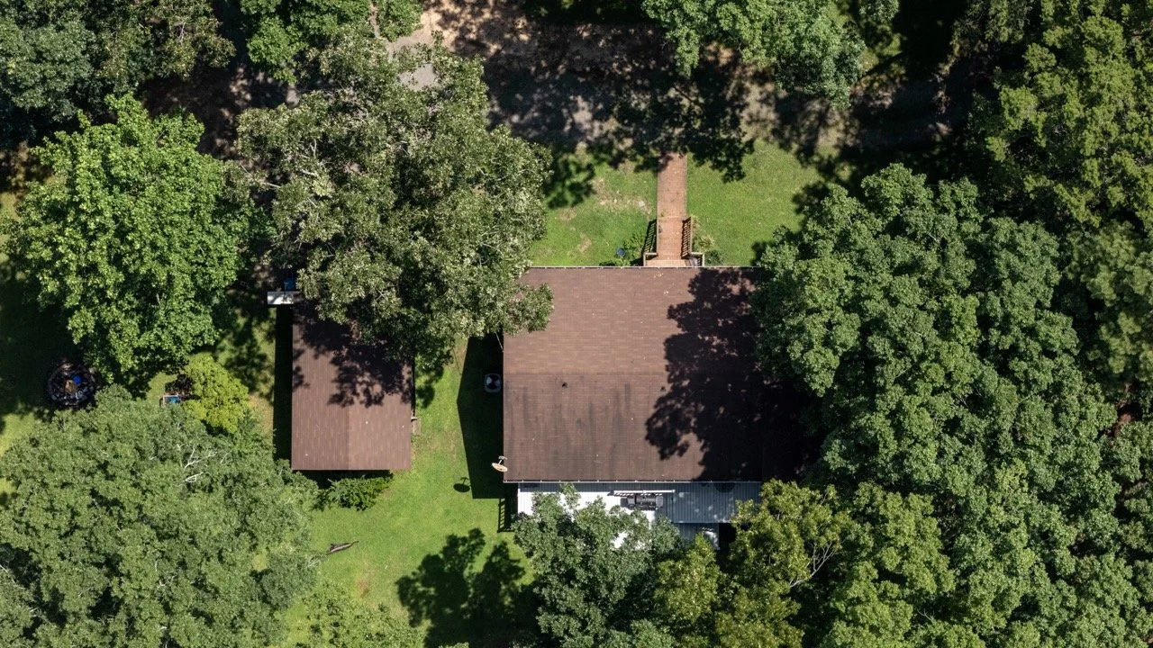 Aerial drone view of residential property with large backyard and surrounding trees in Fayetteville NC