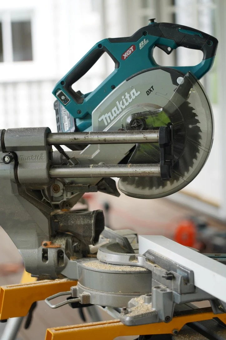 A Makita cordless circular saw mounted on a miter saw stand in a workshop.