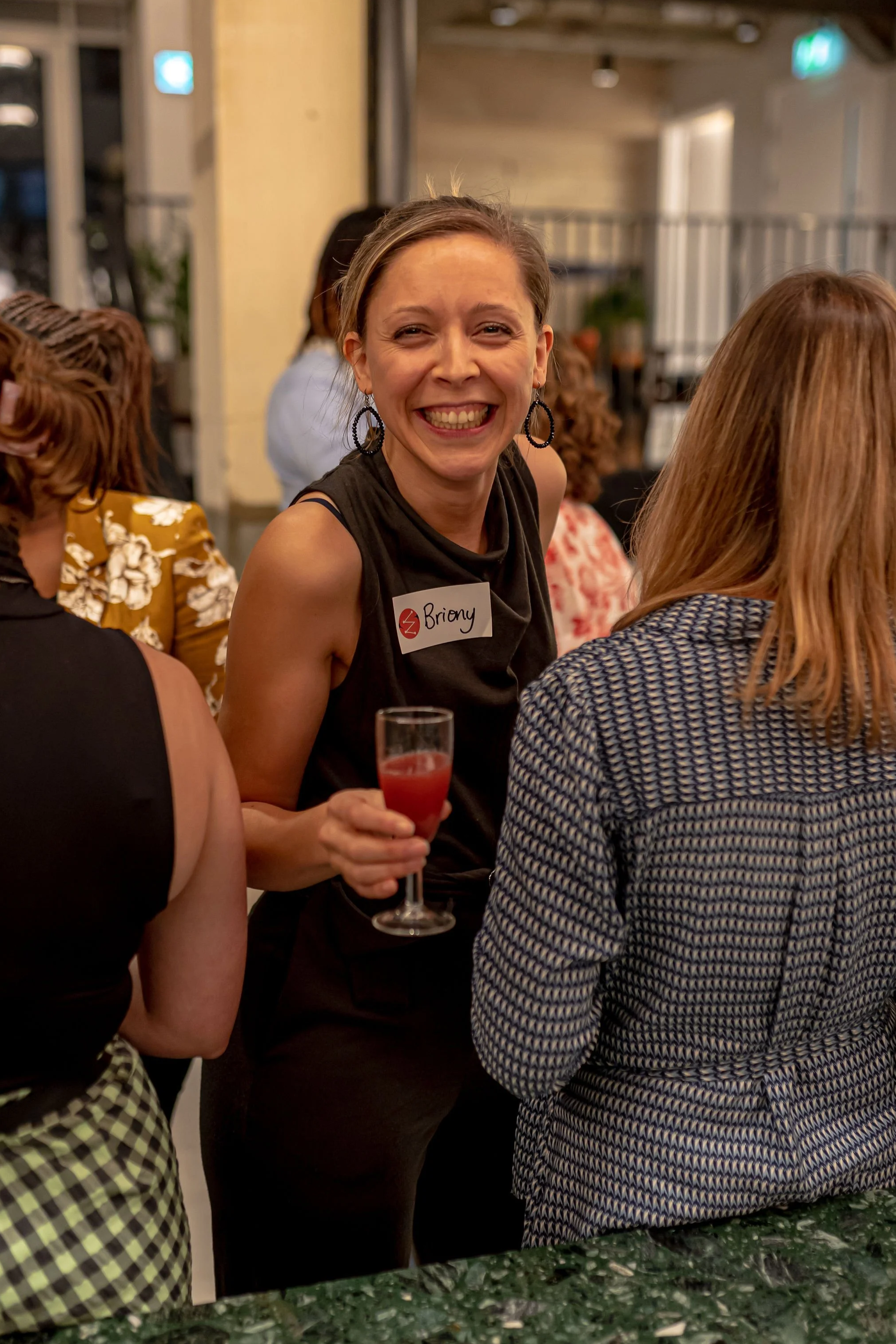 Briony holding a cocktail at Electra event with two women