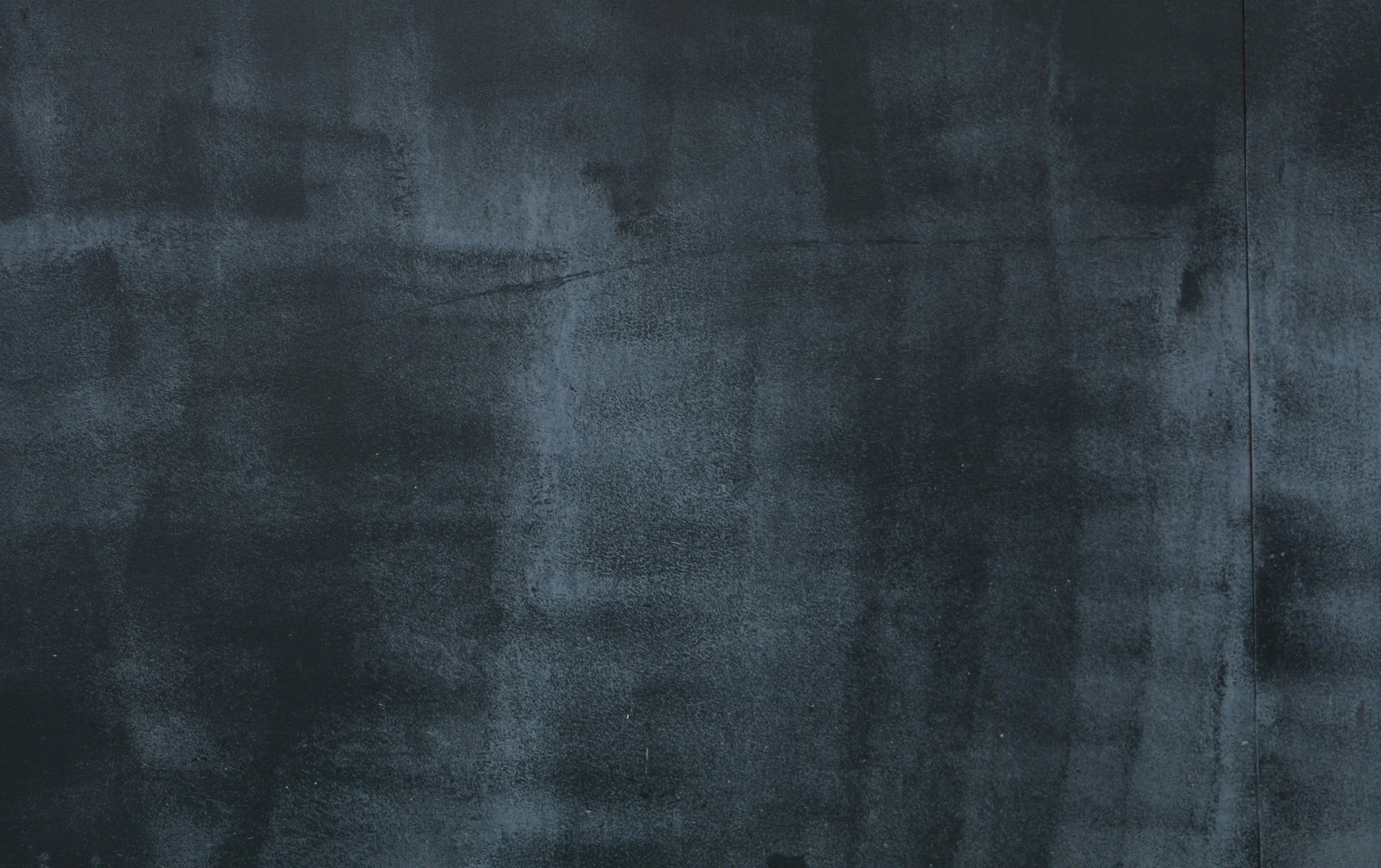 A textured, dark gray surface, possibly a concrete or stone wall.