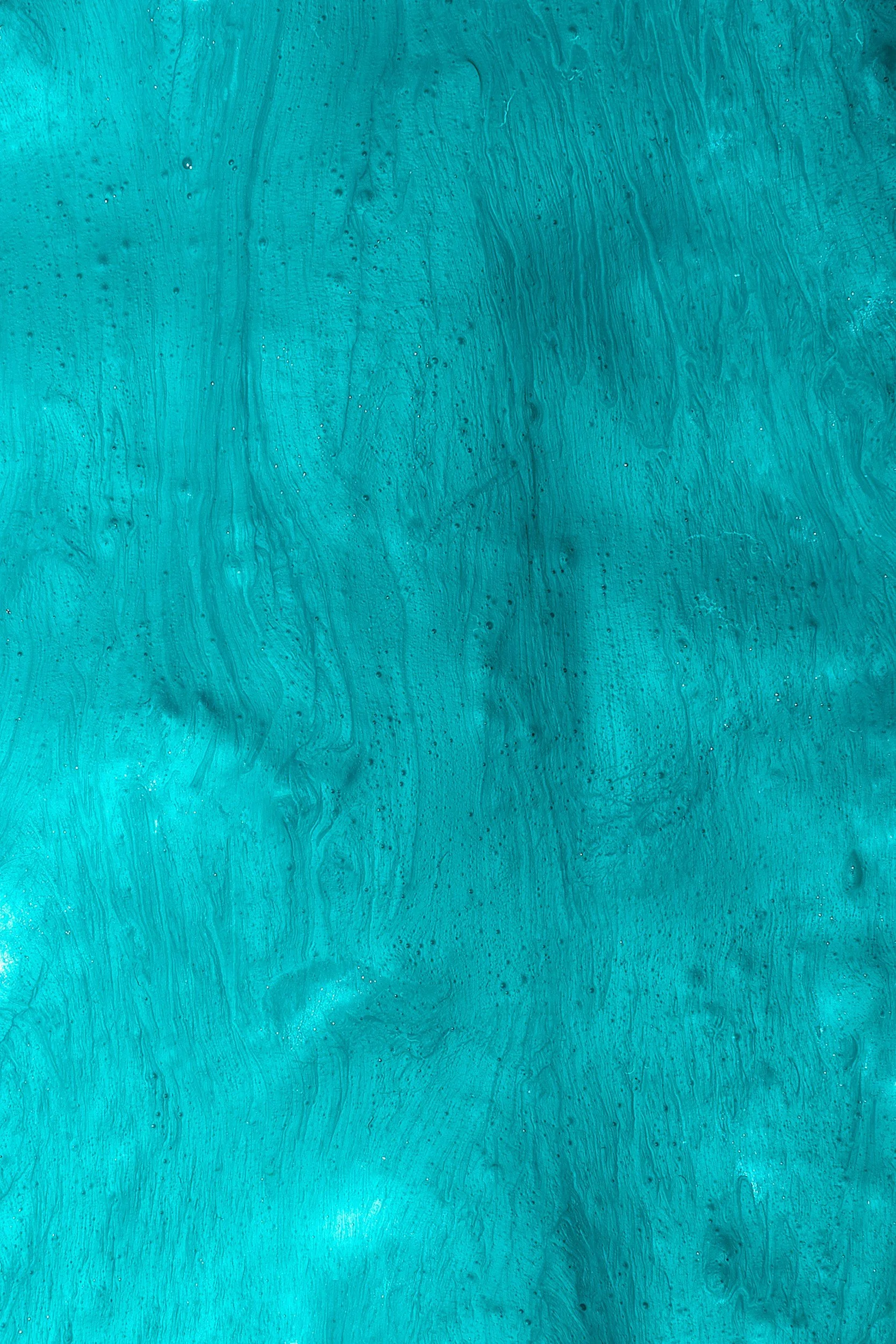 Abstract background with swirling shades of turquoise and teal paint, with small bubbles and streaks creating a textured effect.