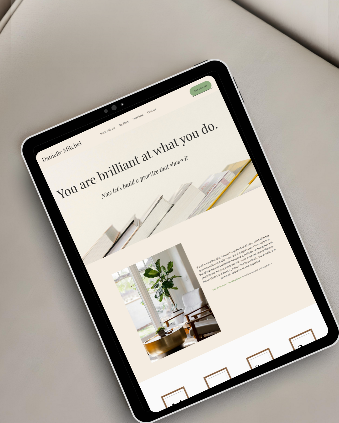 A tablet displaying a website with the headline 'You are brilliant at what you do,' featuring an image of stacked books and a sidebar with a photo of a modern interior with a large plant near a window.