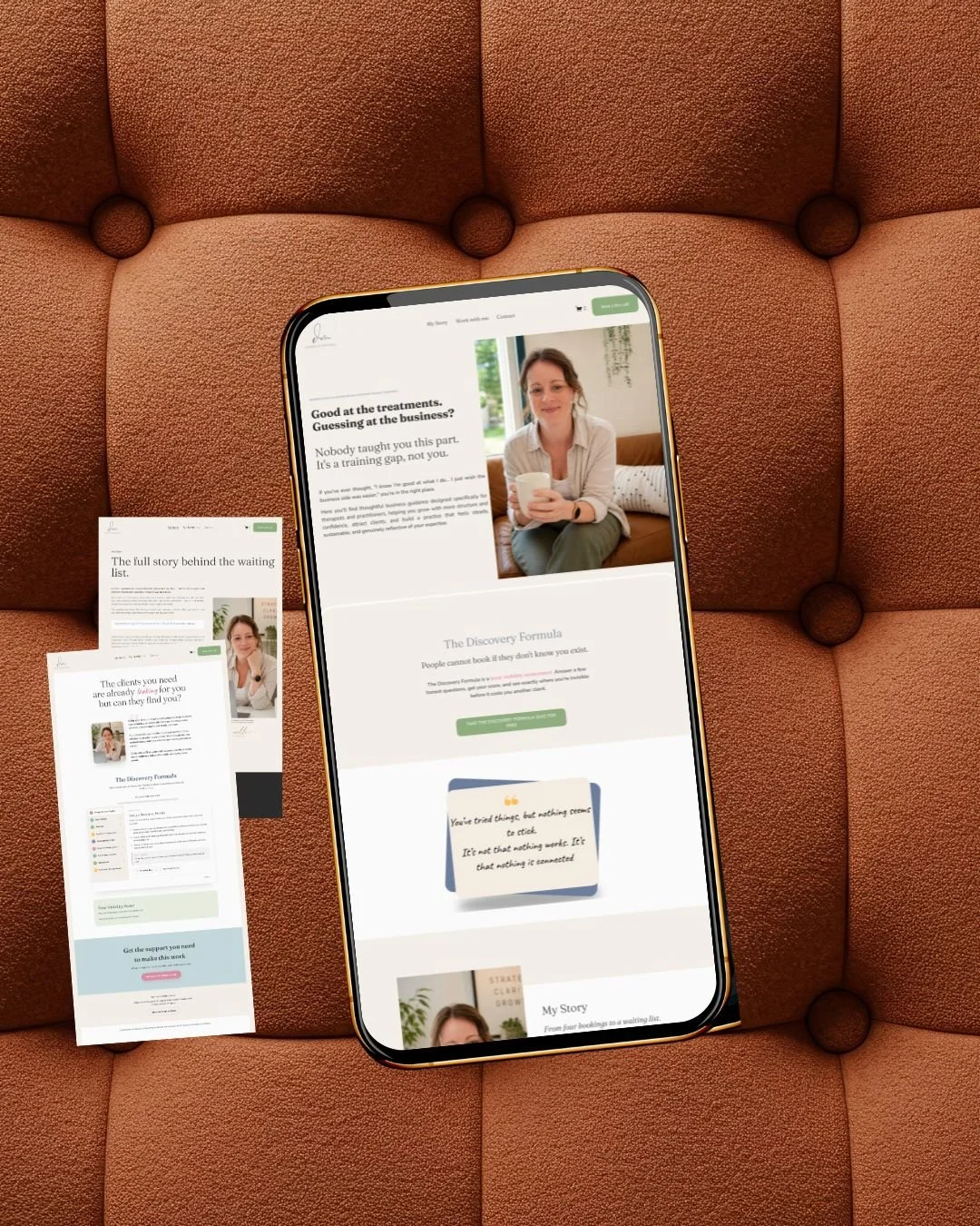 A smartphone displaying a website with a woman holding a mug, sitting on a couch, surrounded by printed pages on a plush, button-tufted brown couch.
