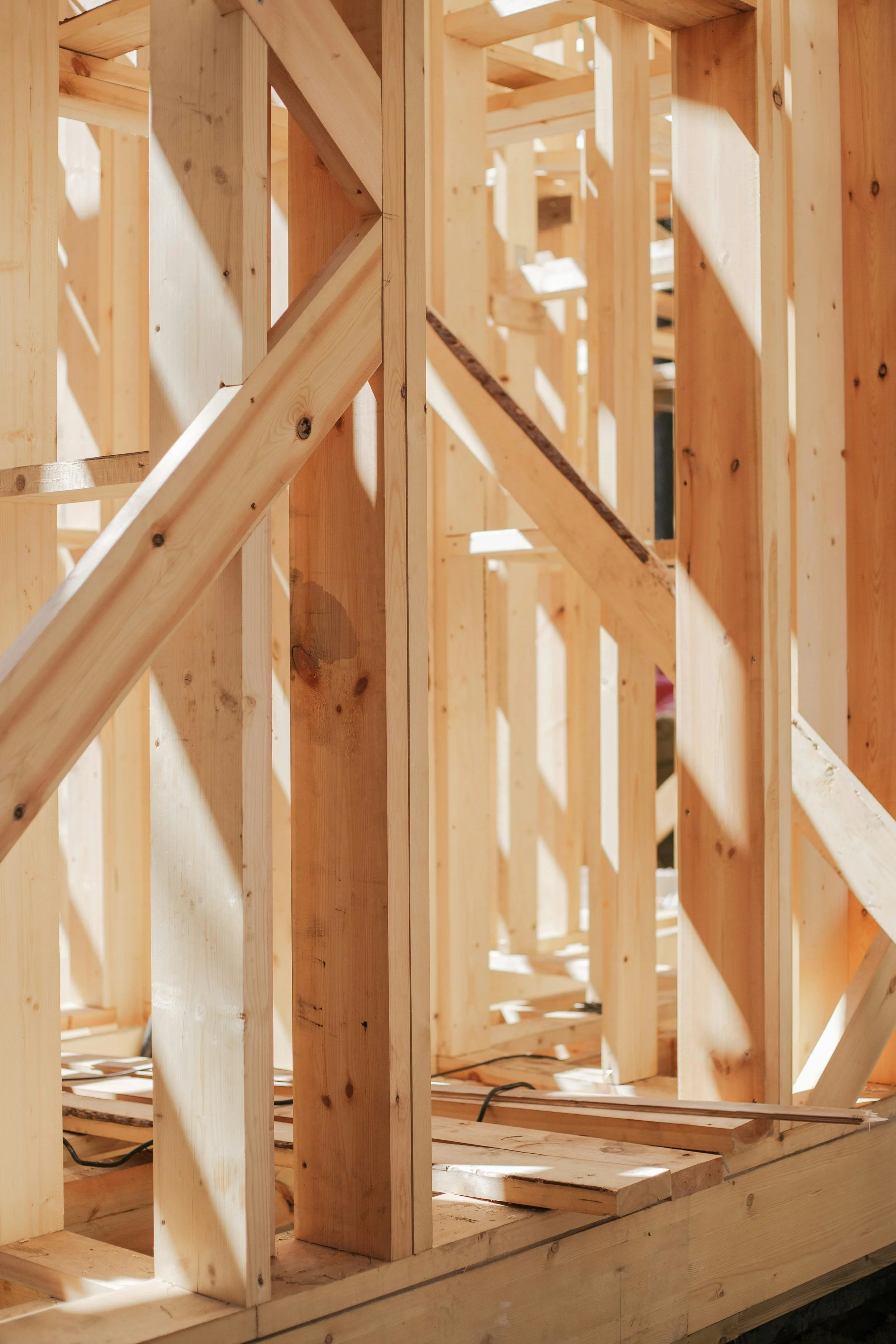 Interior view of a wooden house framing under construction, showing wooden studs and beams. Person in conversation during a virtual healthy home consultation.