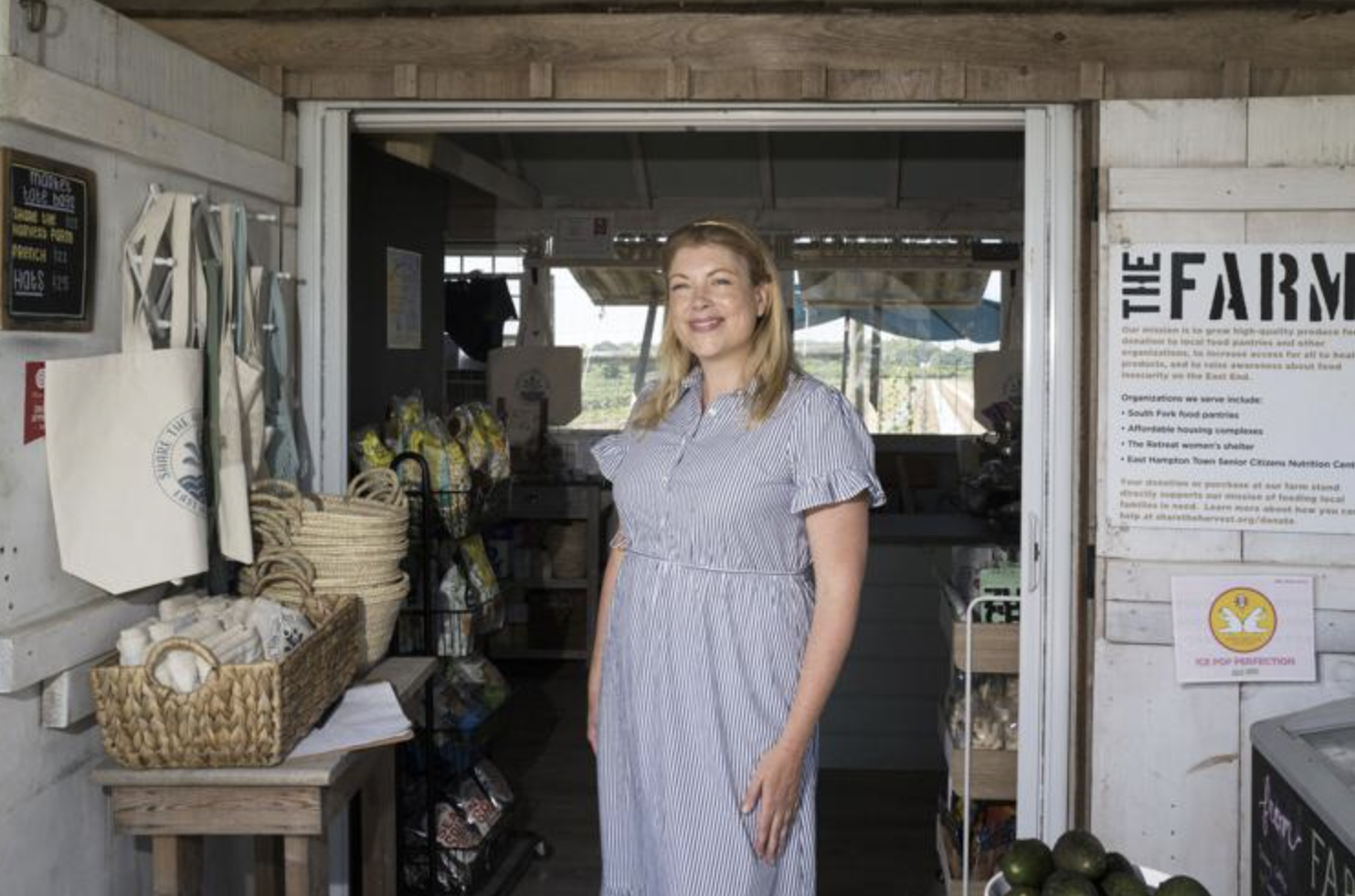 Woman standing in a farm store, smiling, surrounded by produce and farm supplies.