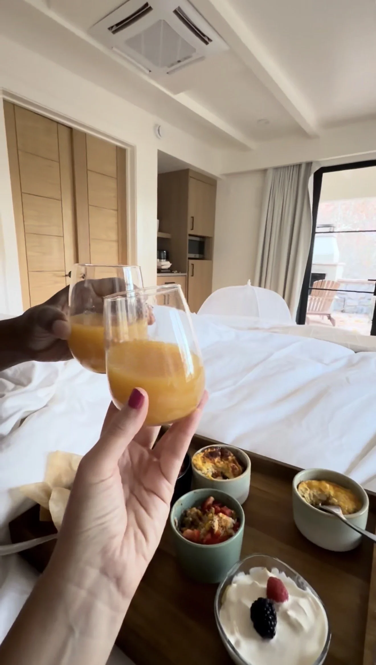 Couple holding drinks in a hotel room with breakfast and a relaxed stay experience, making life an occasion.