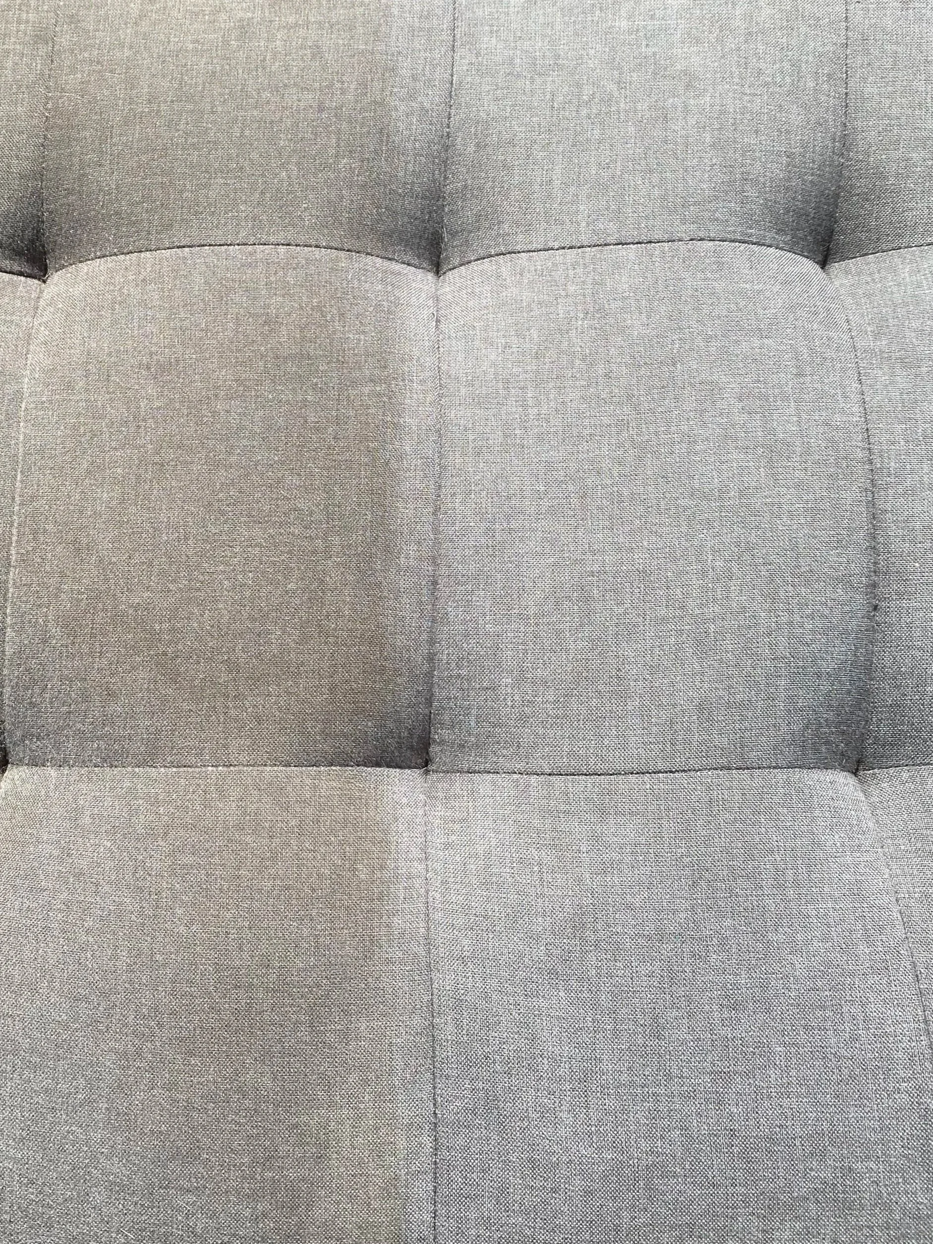 Close-up of a gray upholstered fabric chair with tufted detail and visible stitching. Showing dirty and clean side.