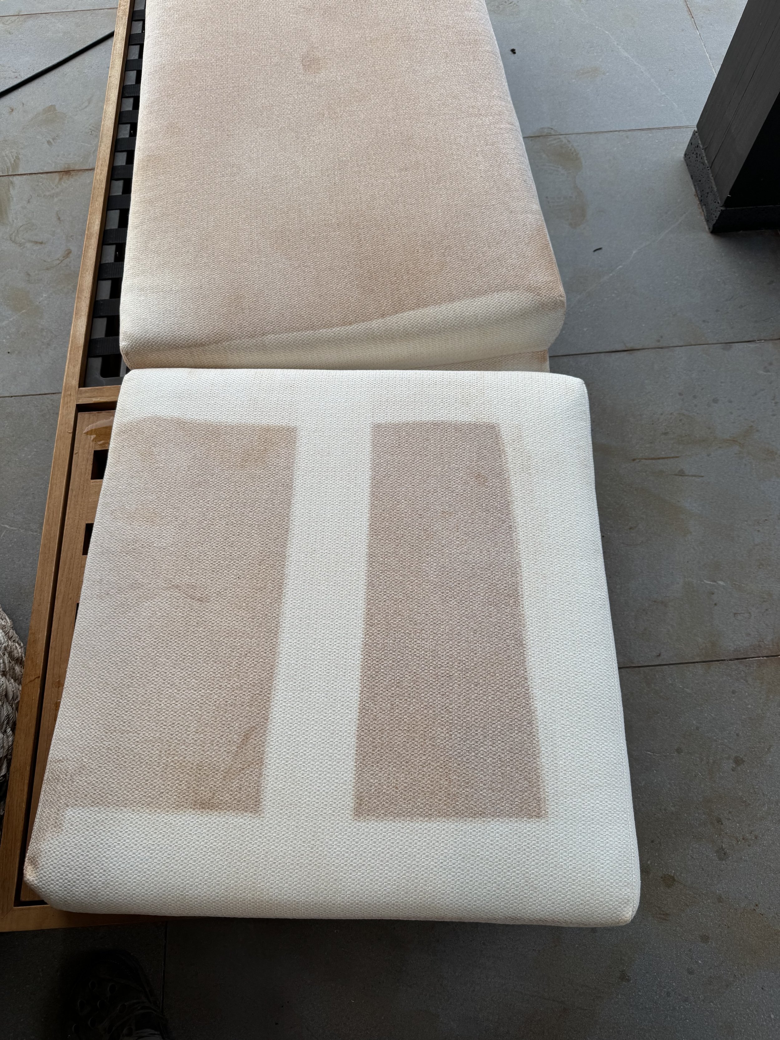 Two cushioned seats with beige and white fabric upholstery, placed on a stone or concrete floor.