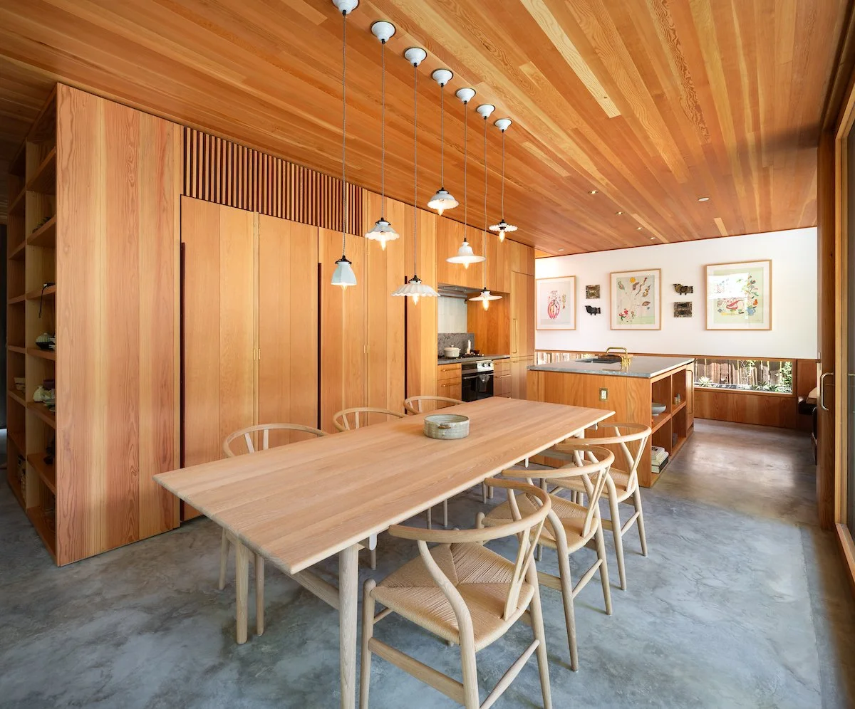 Dining room with concrete floors and a modern custom wood table, walls and ceiling