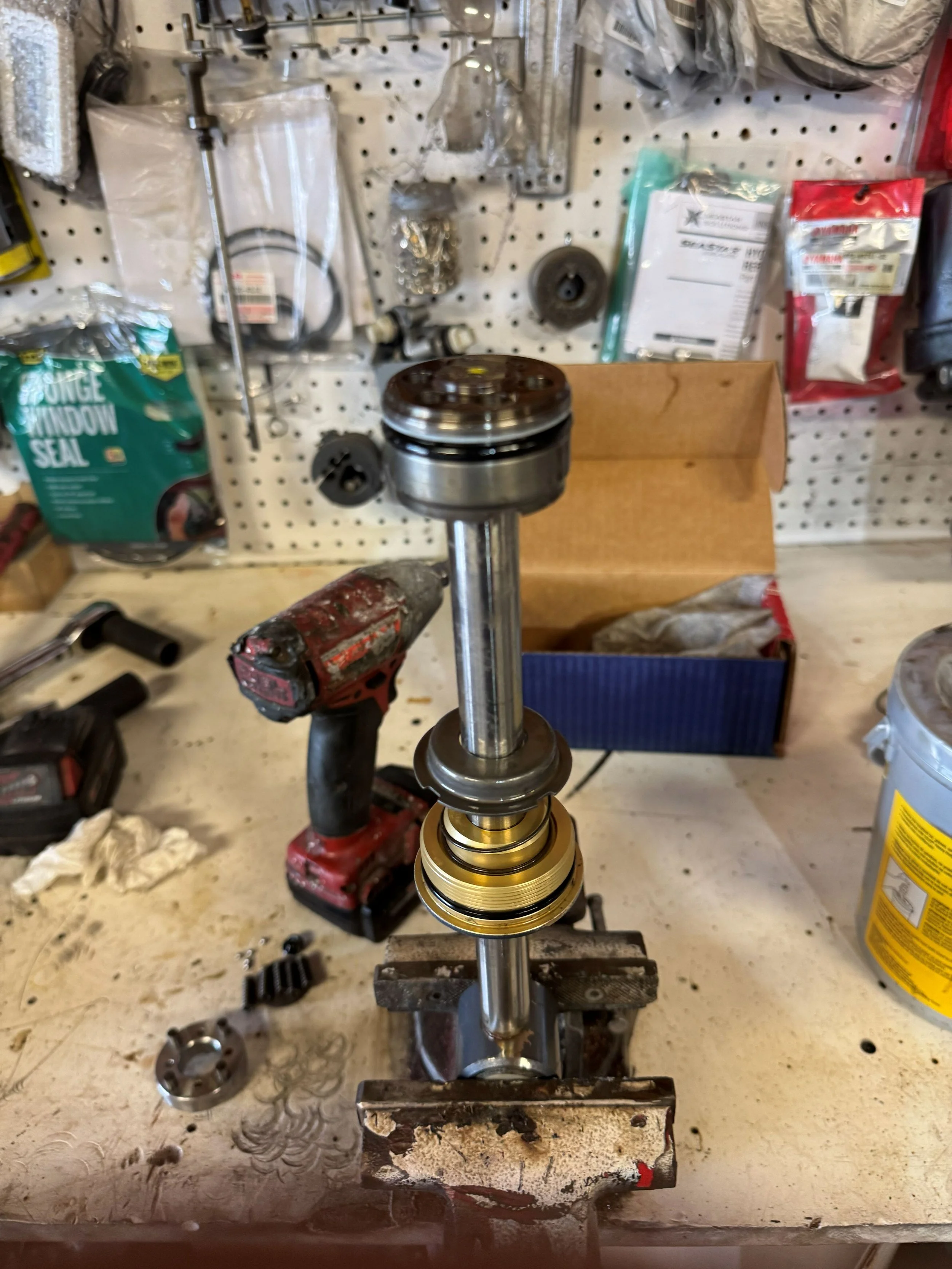 A workbench with a partially assembled piston and connecting rod in a garage or workshop setting.