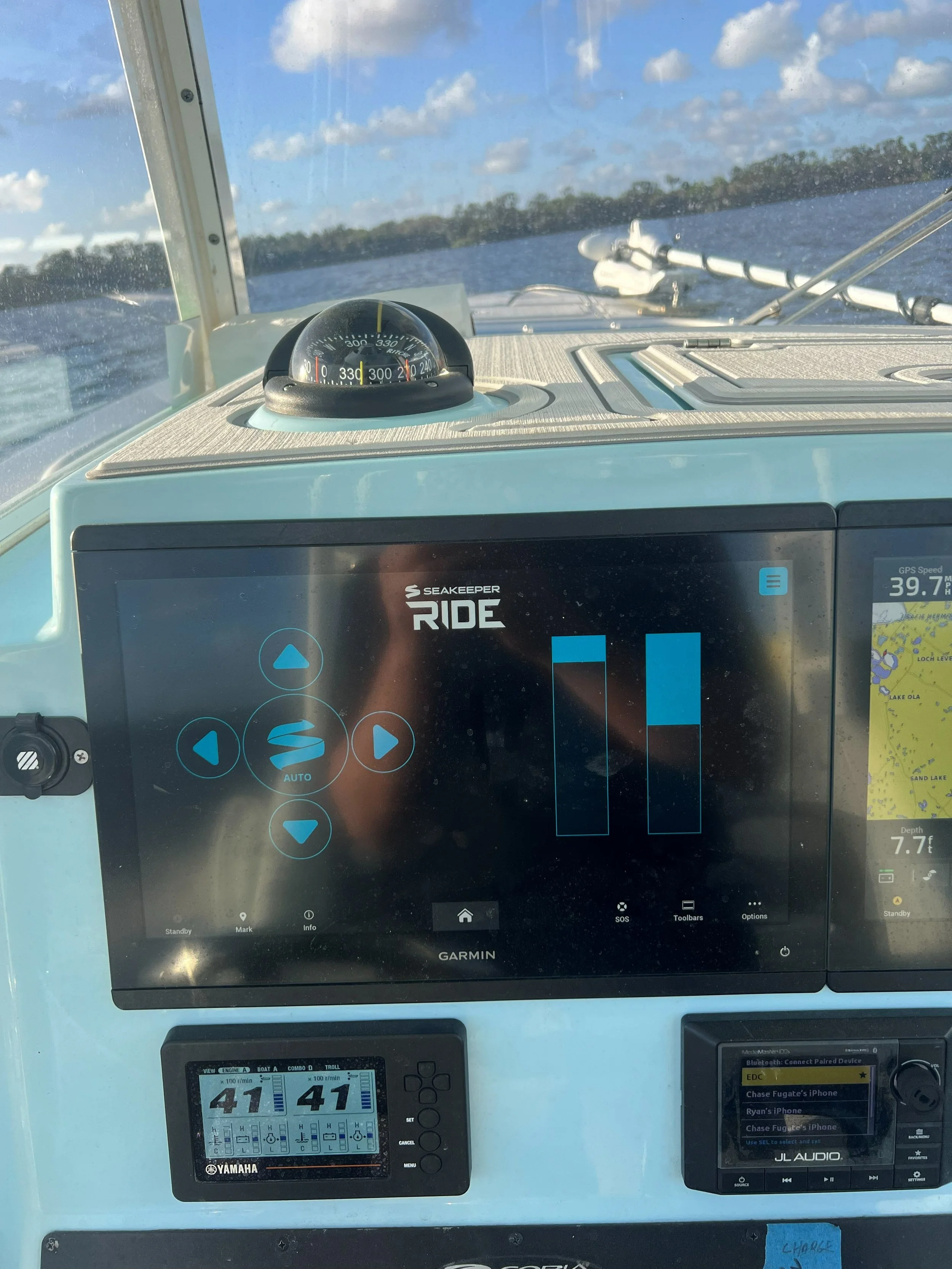 Dashboard of a boat with GPS and navigation systems, compass, and water view.