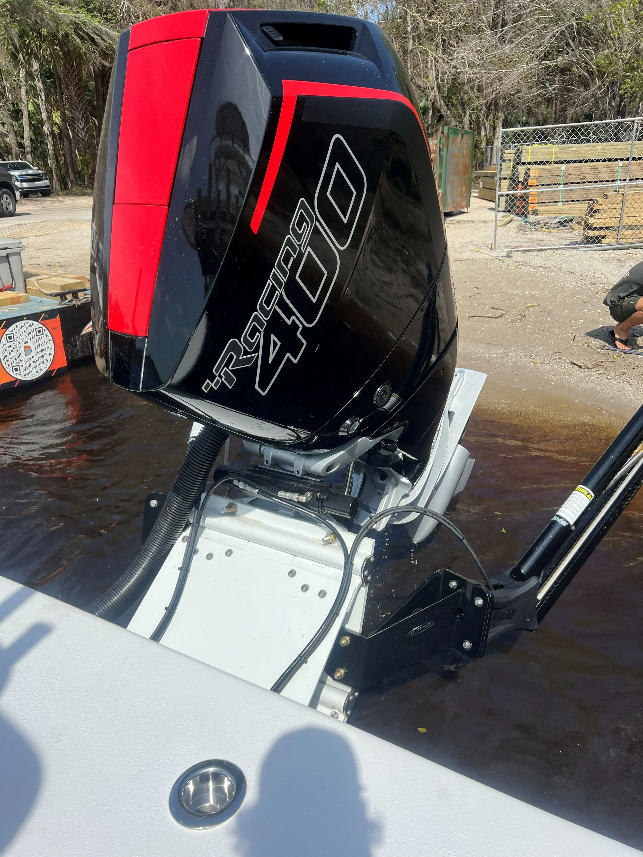 Outboard motor engine attached to a boat in water, with a black and red casing and the label 'RACING 40'.