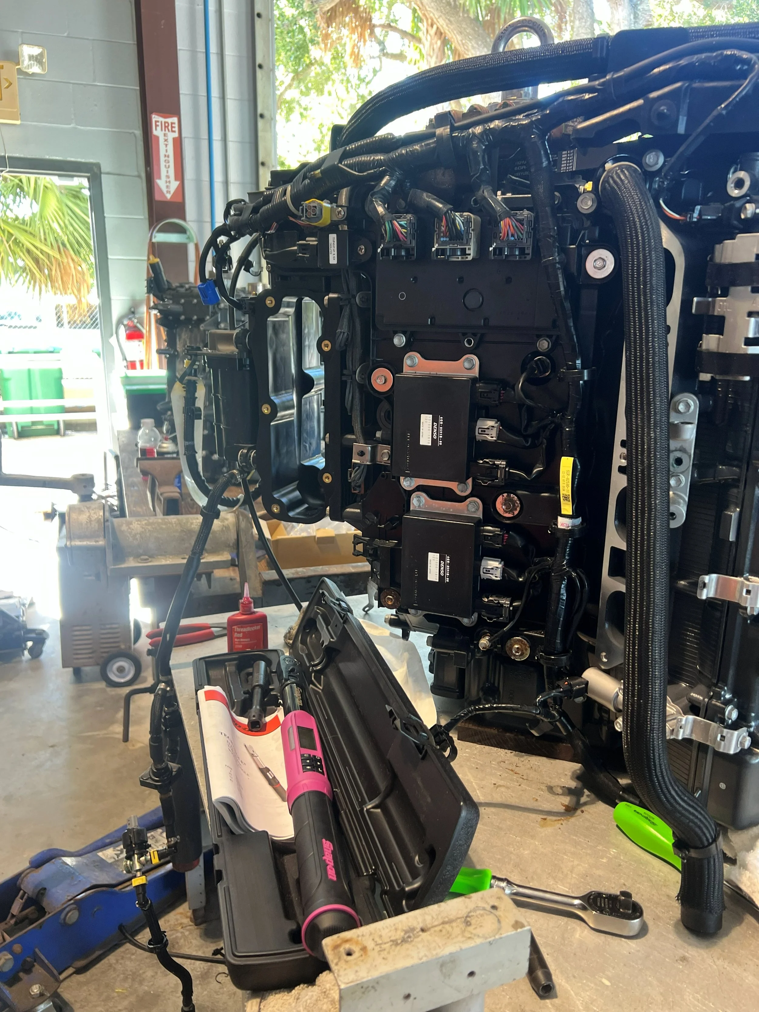 Automotive engine being worked on in a workshop with tools and parts around.