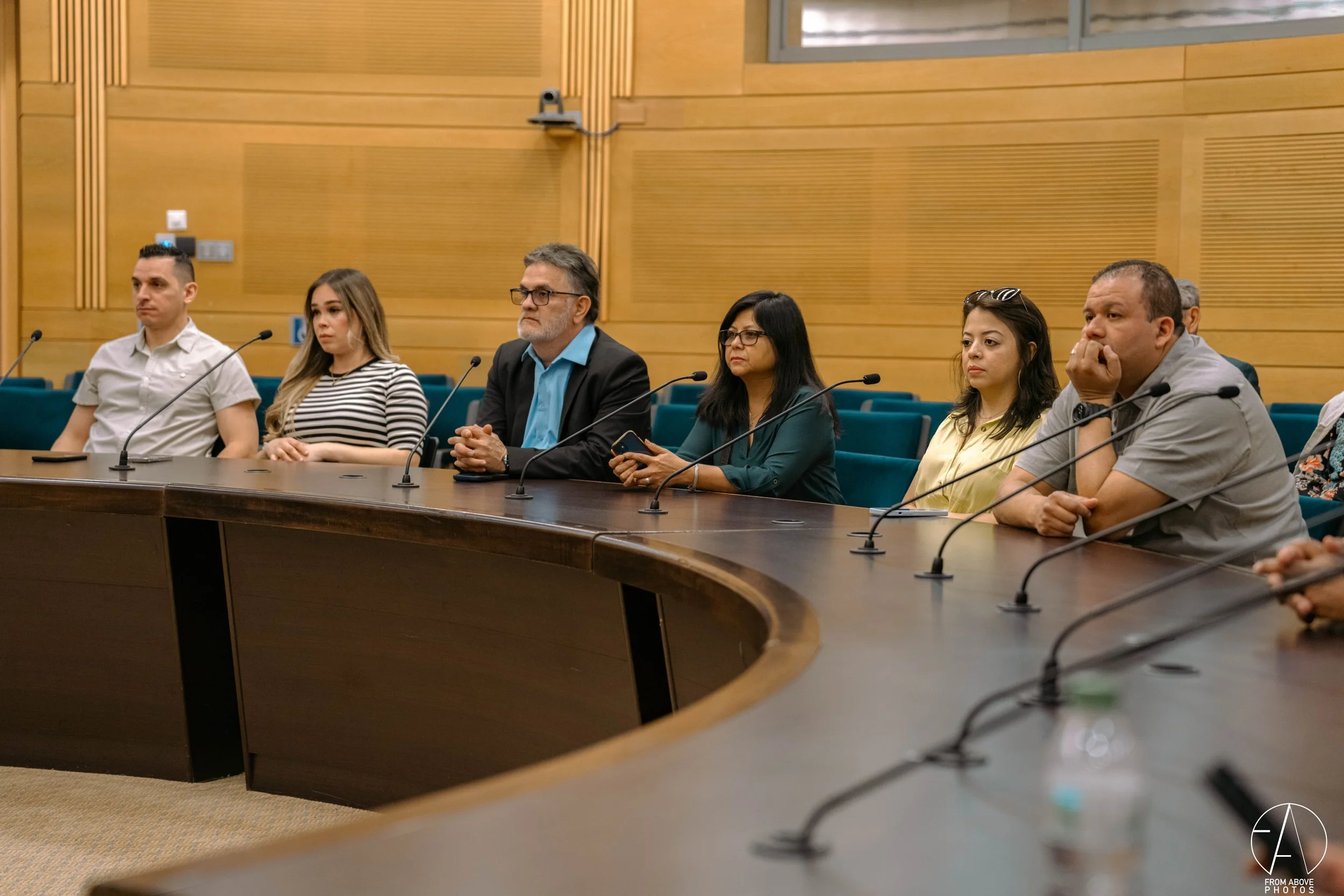 People sitting at a conference table with microphones, listening attentively.