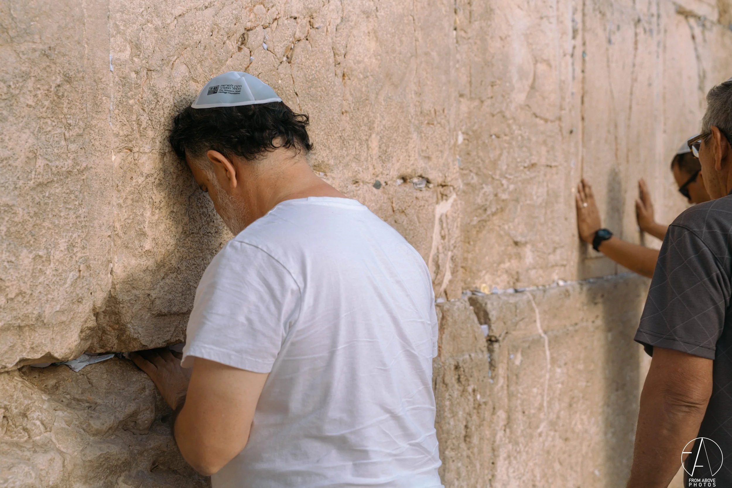 People praying at the Western Wall in Jerusalem, touching the ancient stones with their hands.