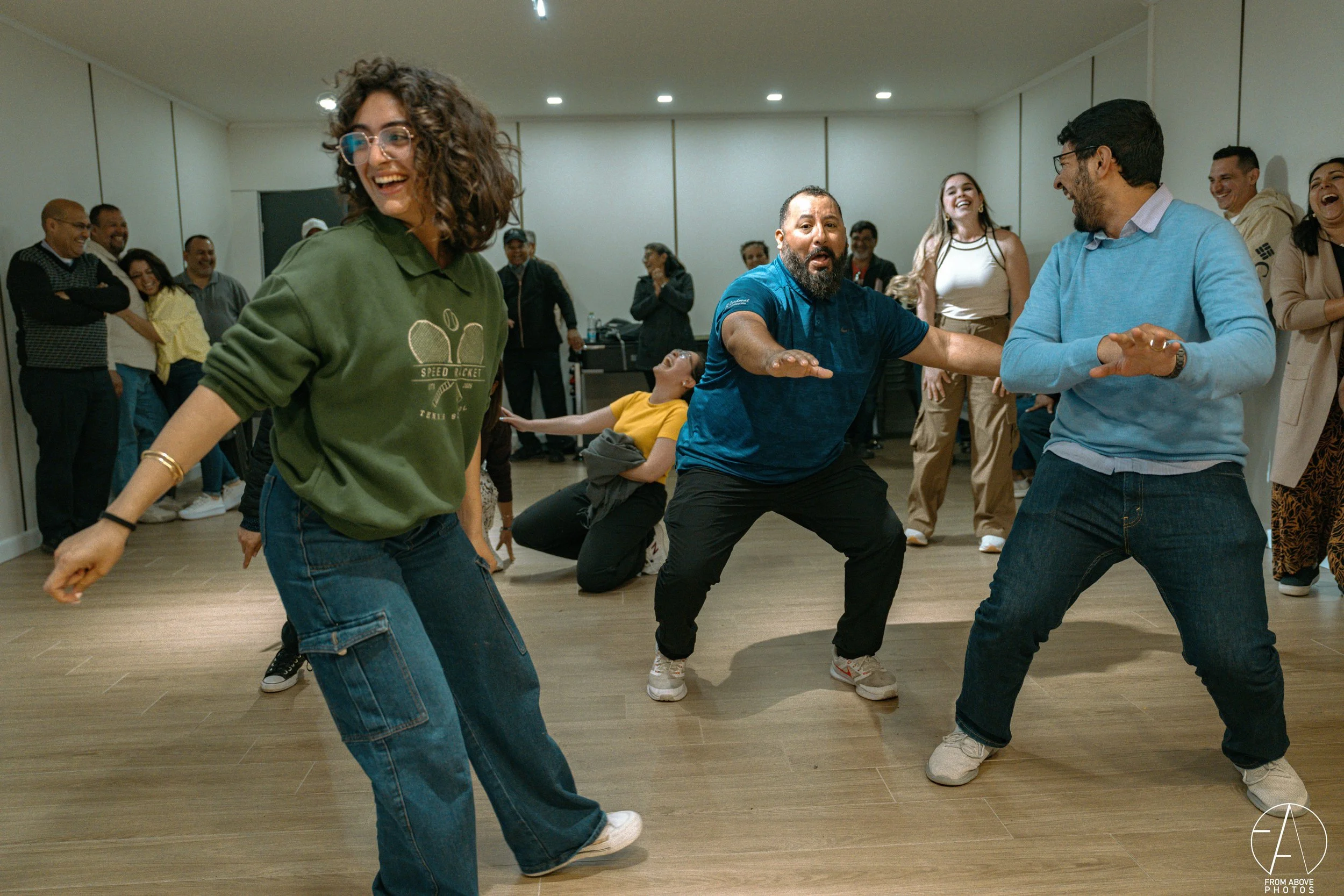 People dancing and having fun at a party or social gathering indoors, with smiles and laughter.