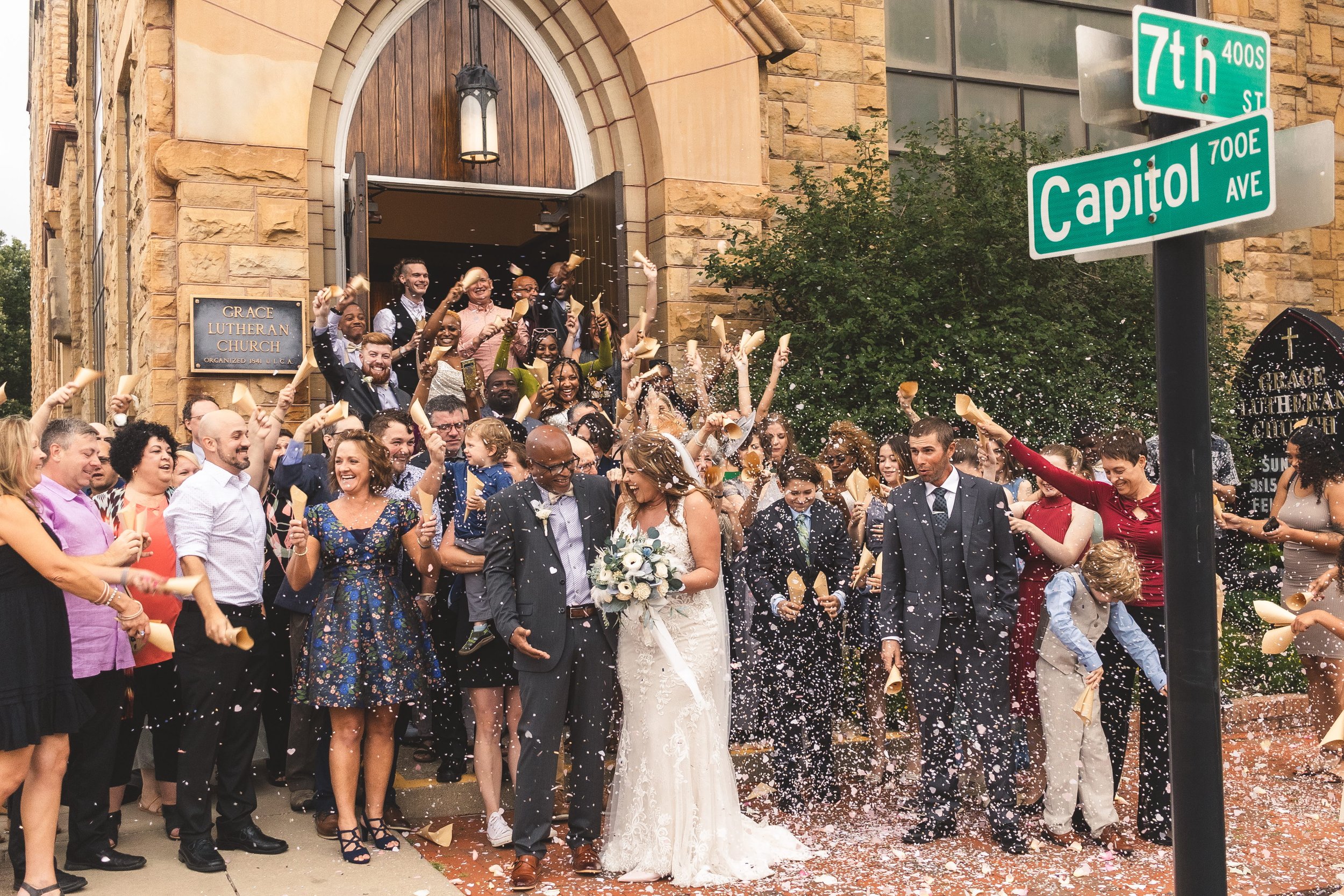 Bride and groom exiting Grace Lutheran Church as guests celebrate with a confetti send-off after their wedding ceremony