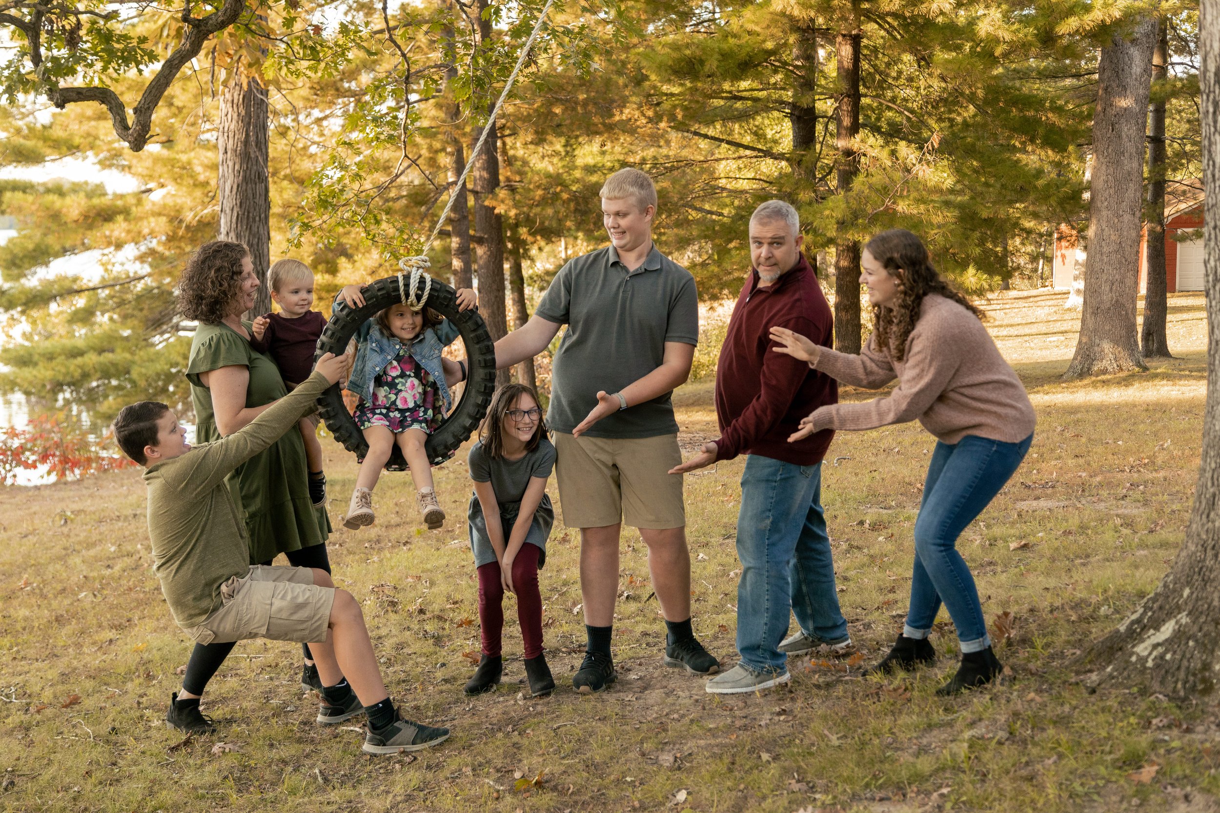 Large multigenerational family group portrait surrounded by vibrant fall foliage
