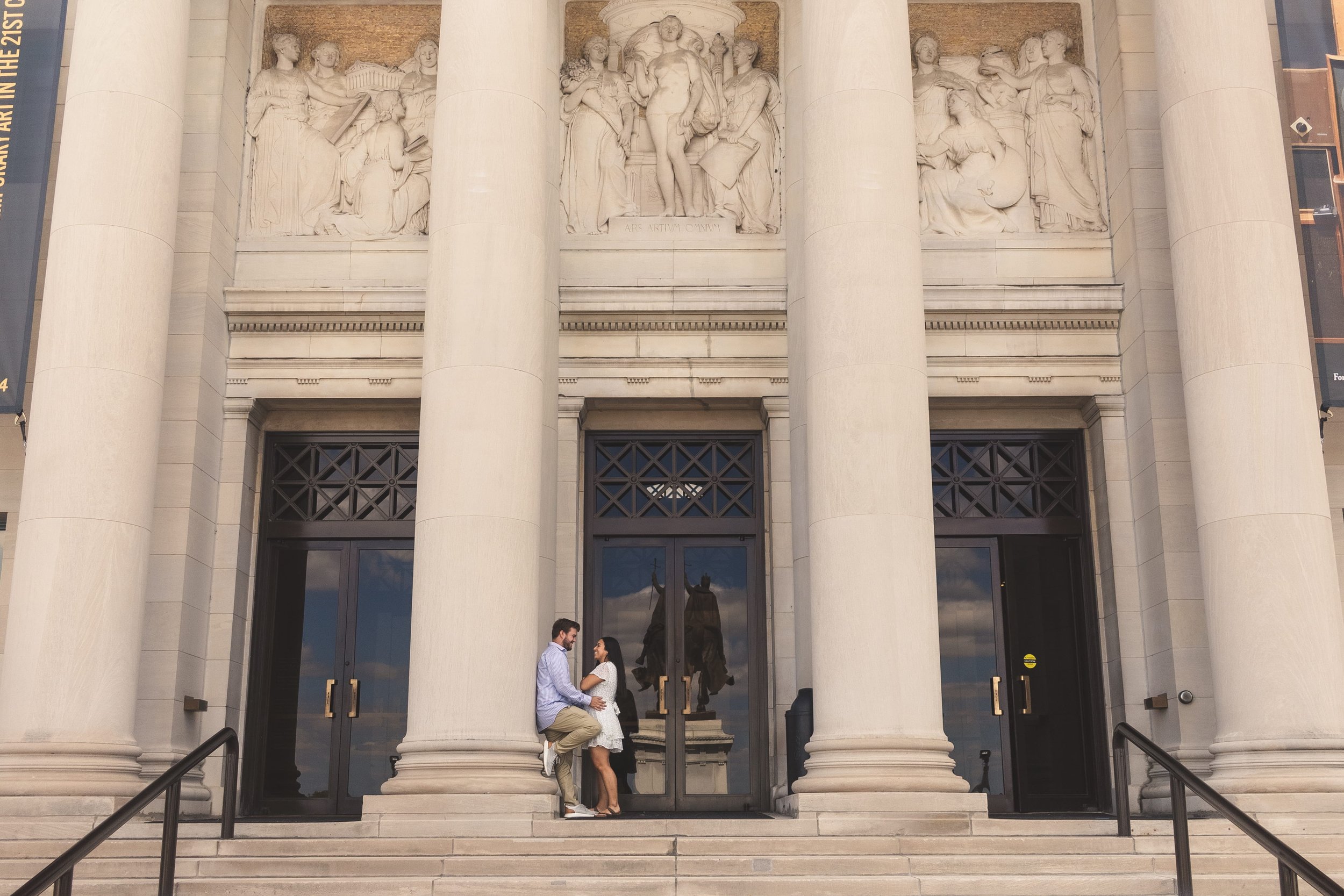 Couple posing together on the steps of a grand neoclassical building with tall stone columns