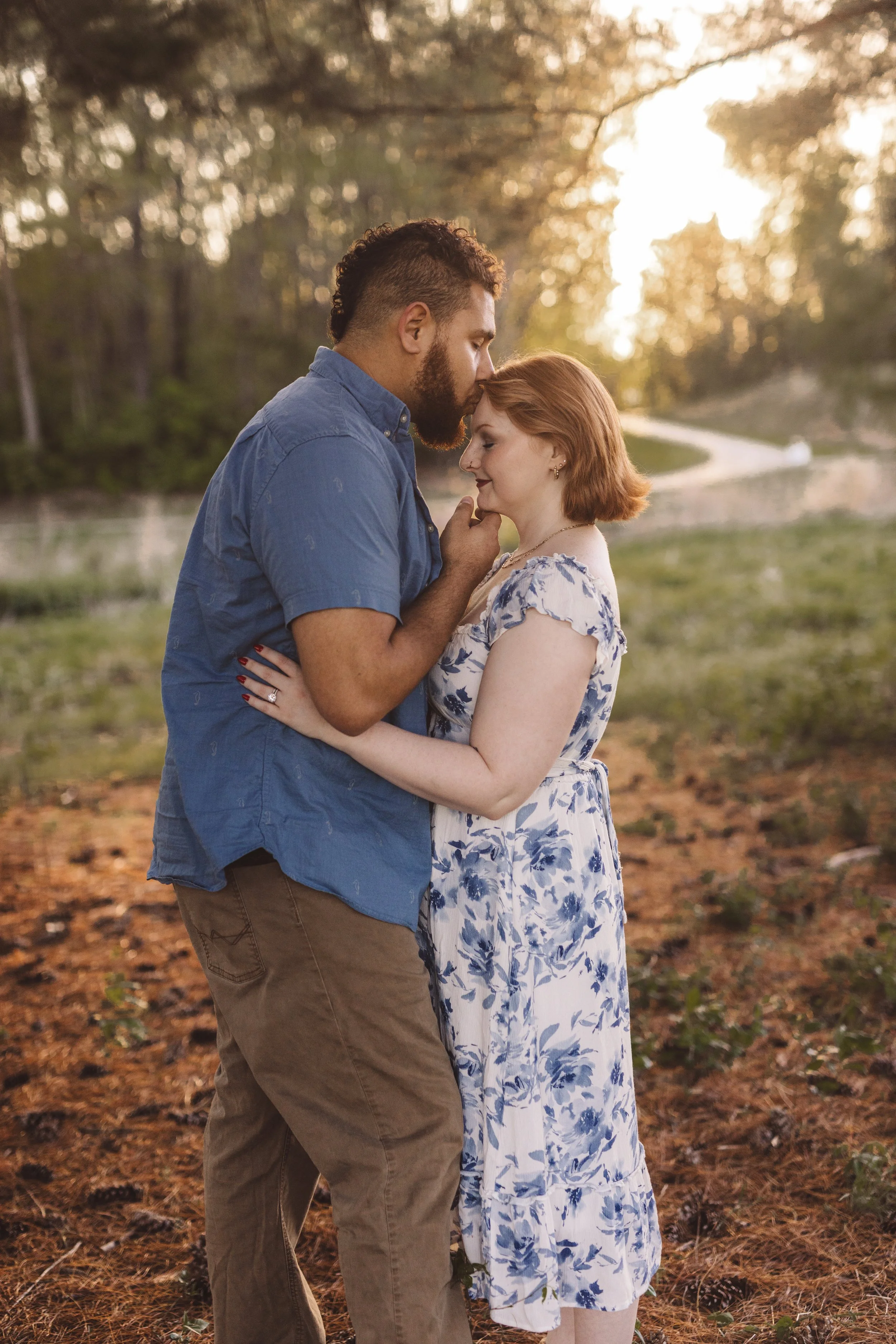Couple embracing at golden hour during an outdoor engagement session in a wooded setting
