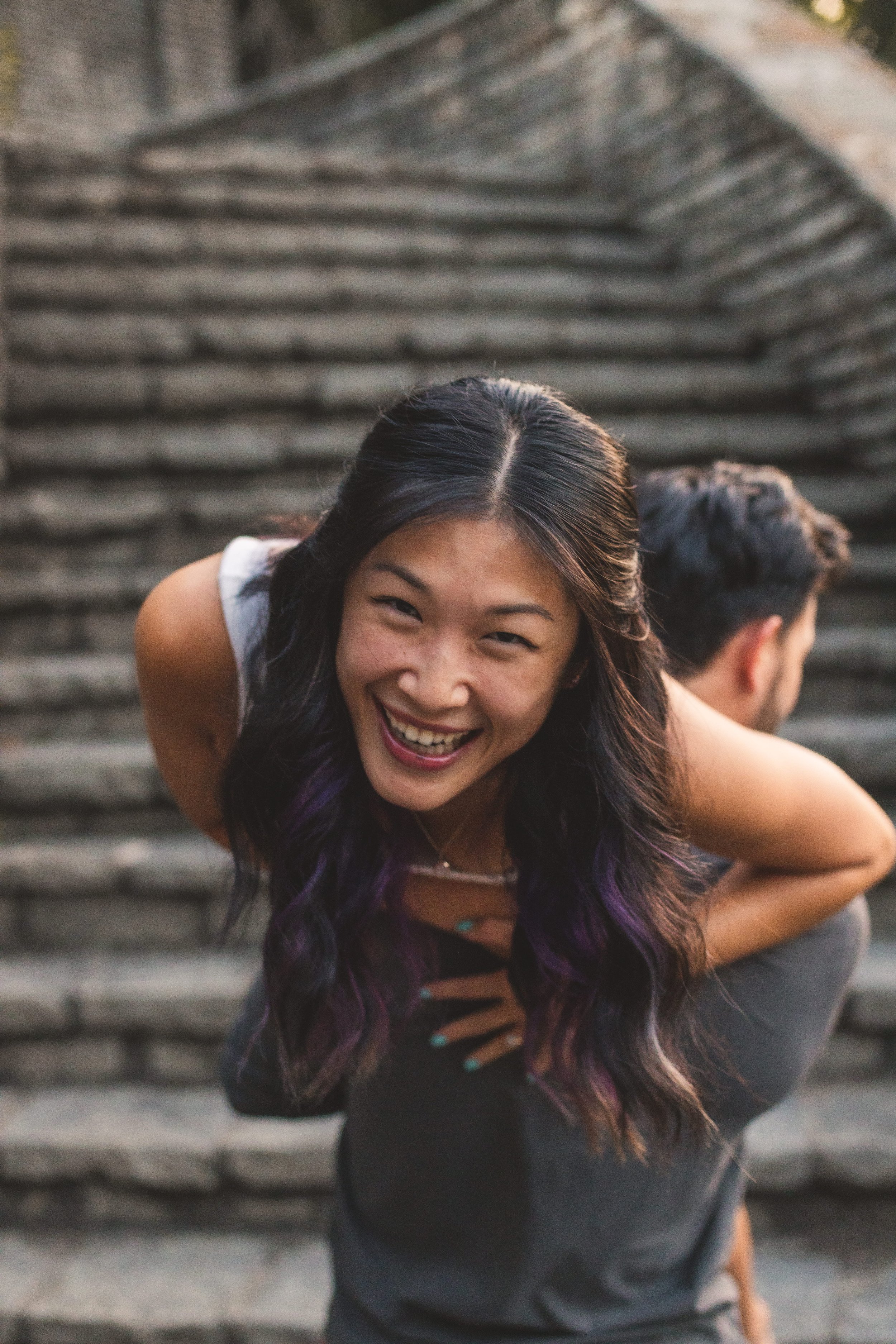 Young woman laughing on stone steps during senior portrait session, natural and candid