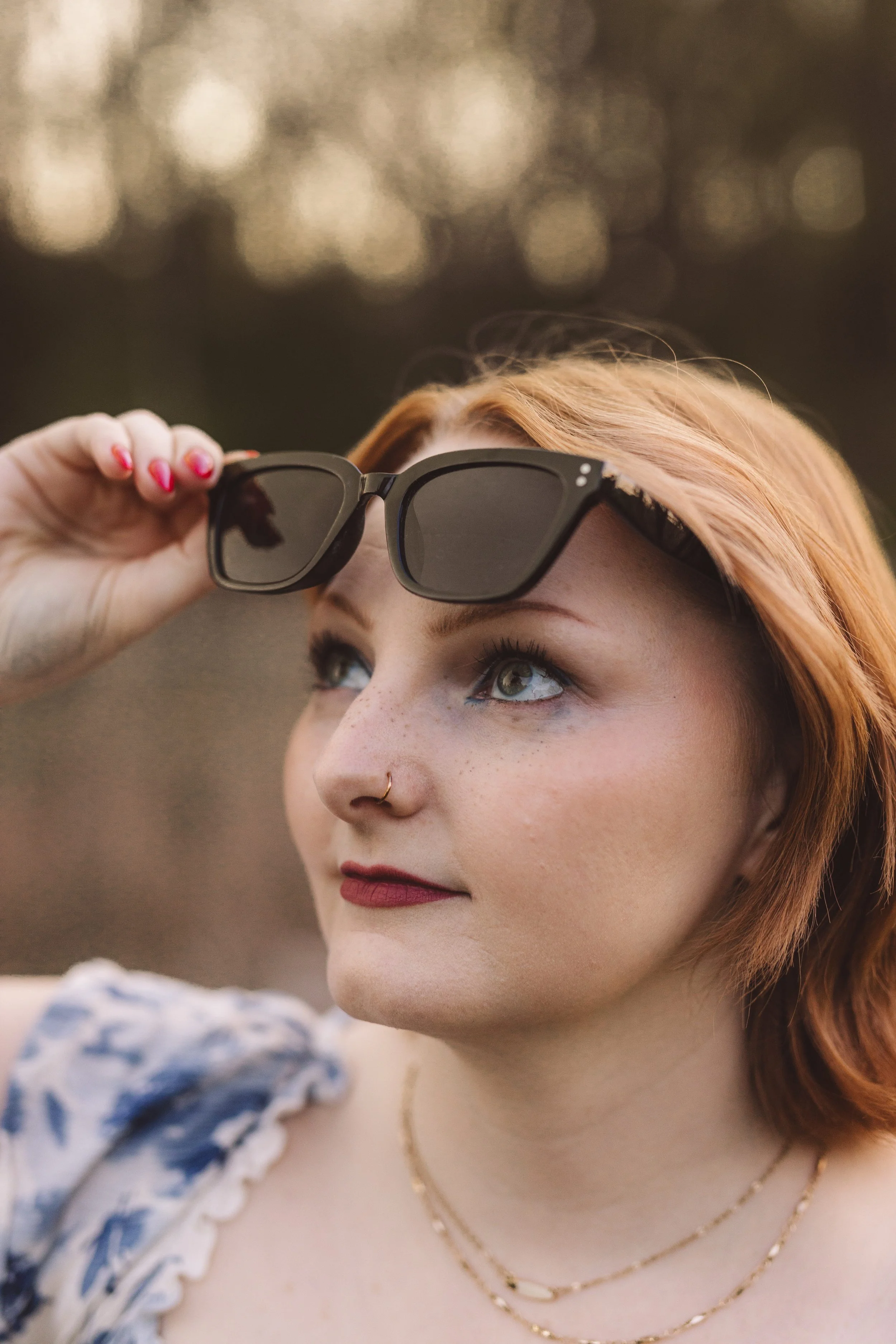 Addie Evers, co-founder of Evers & Co. Media, lifting her sunglasses during an outdoor portrait session