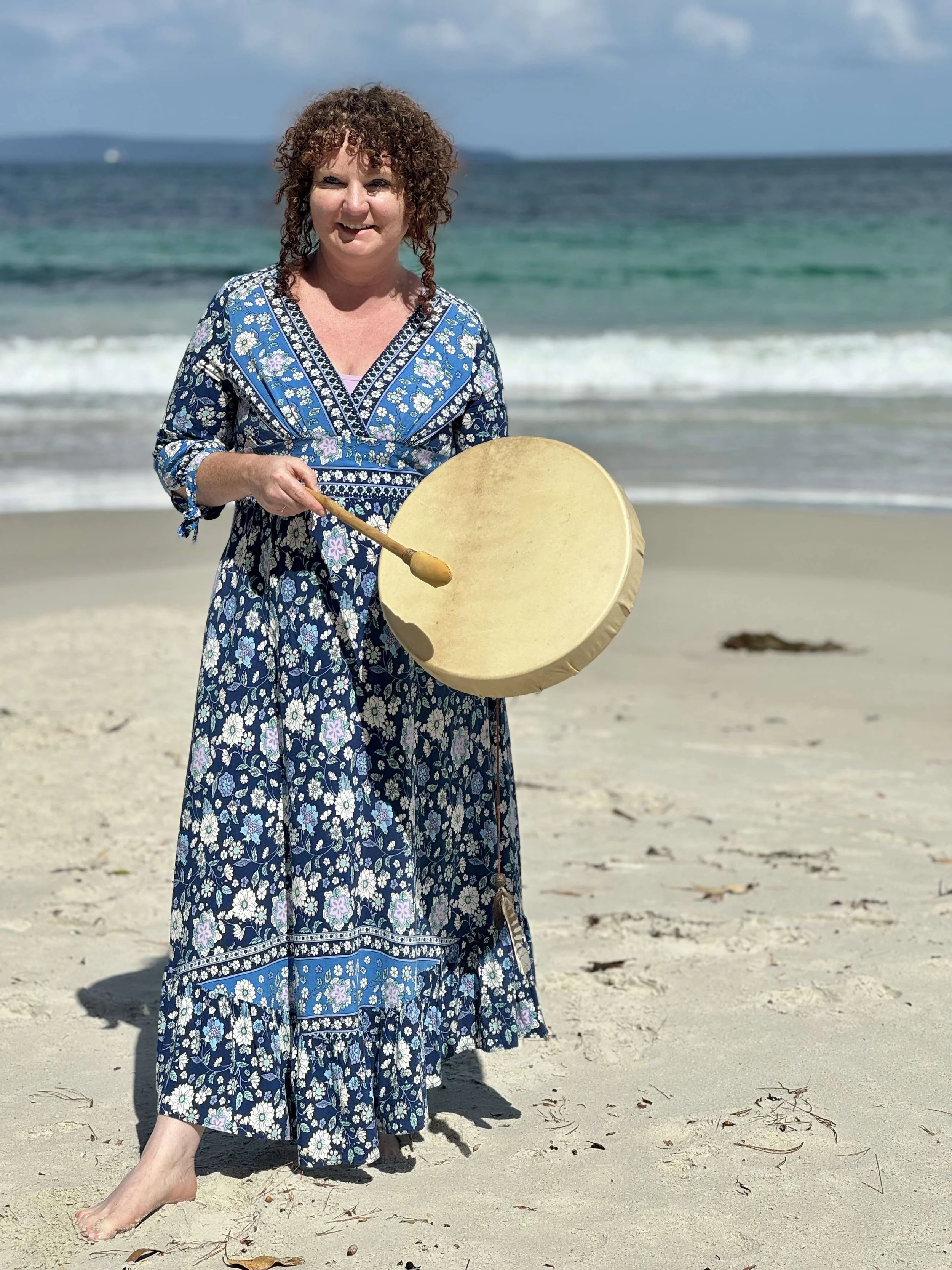 Sound healing practitioner holding a drum on a beach in Hobart, Tasmania