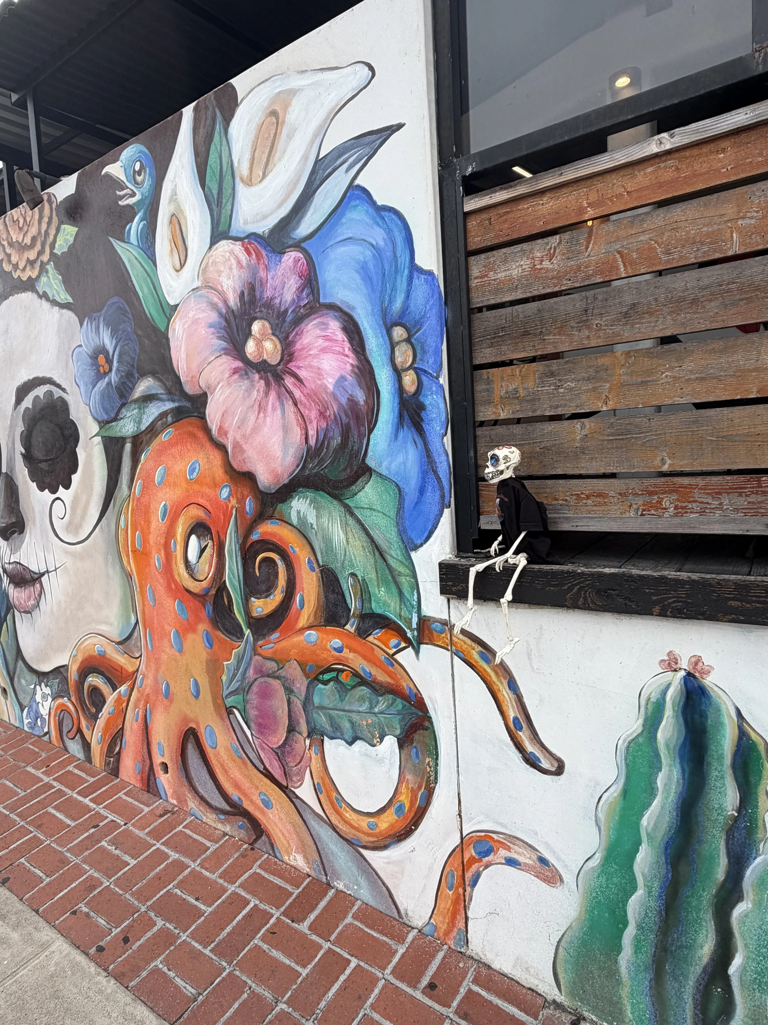 Huesito sitting beside the colorful octopus mural at La Esquinas in Old Town San Diego.